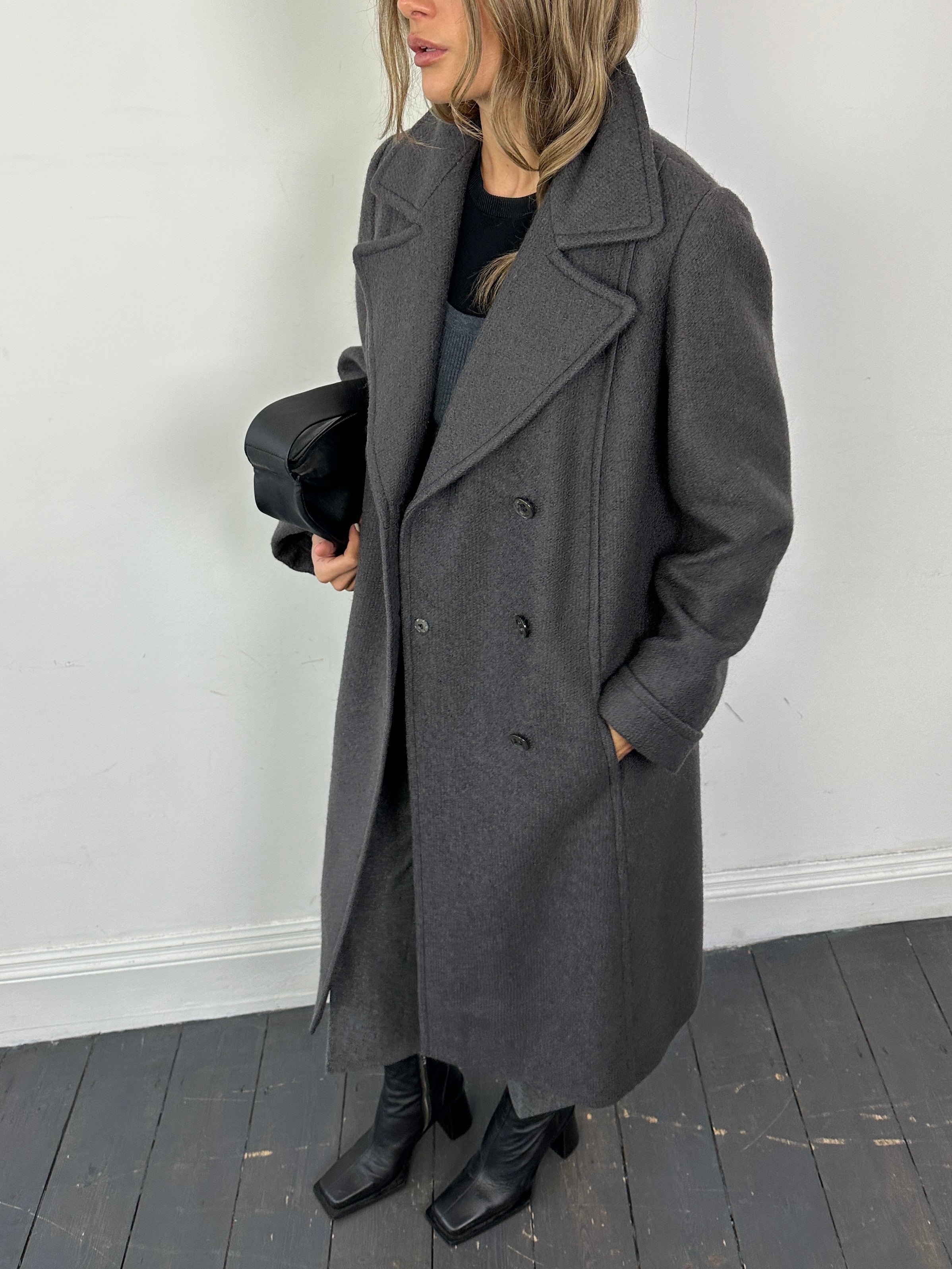 Vintage wool double-breasted A-line coat in classic style, shown in natural light on a hanger with visible buttons and lapel details.