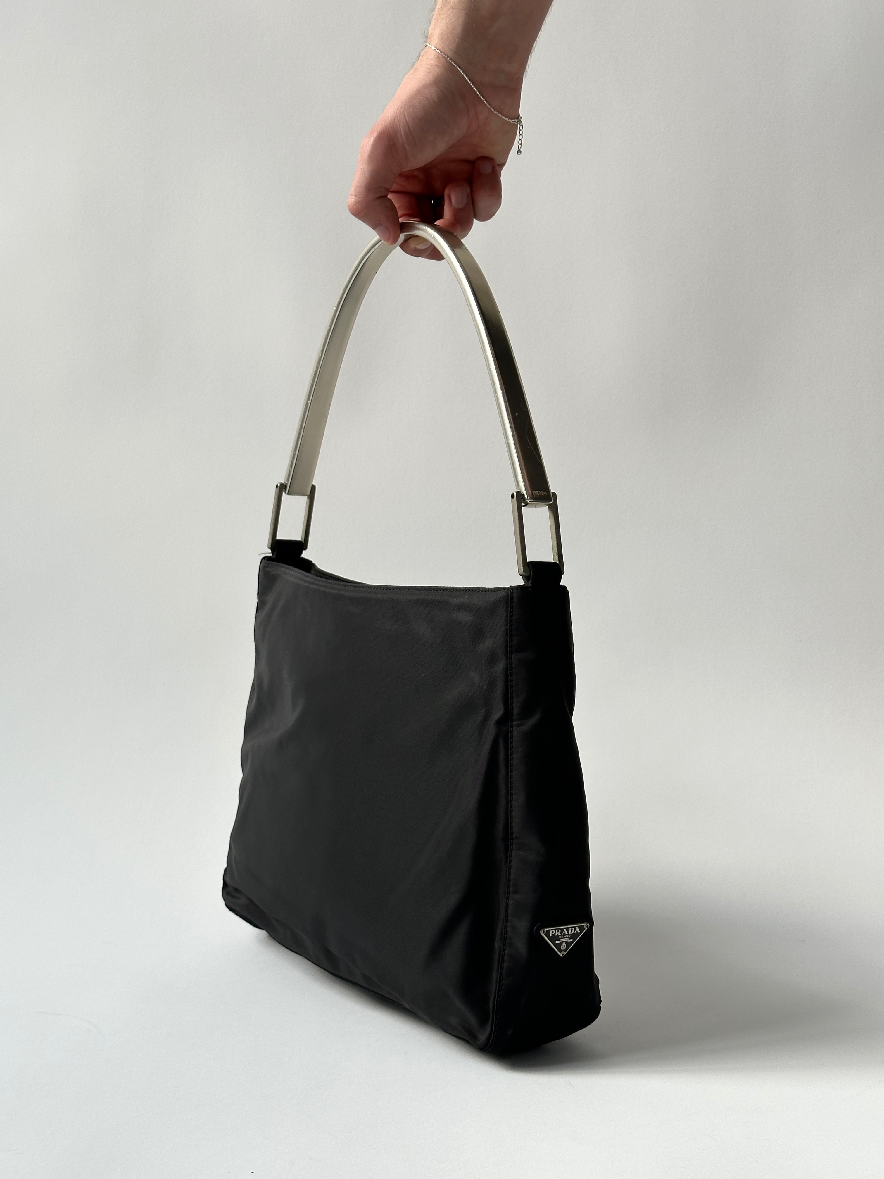Prada nylon shoulder bag with metal handle, featuring a sleek design and durable strap, ideal for everyday use.