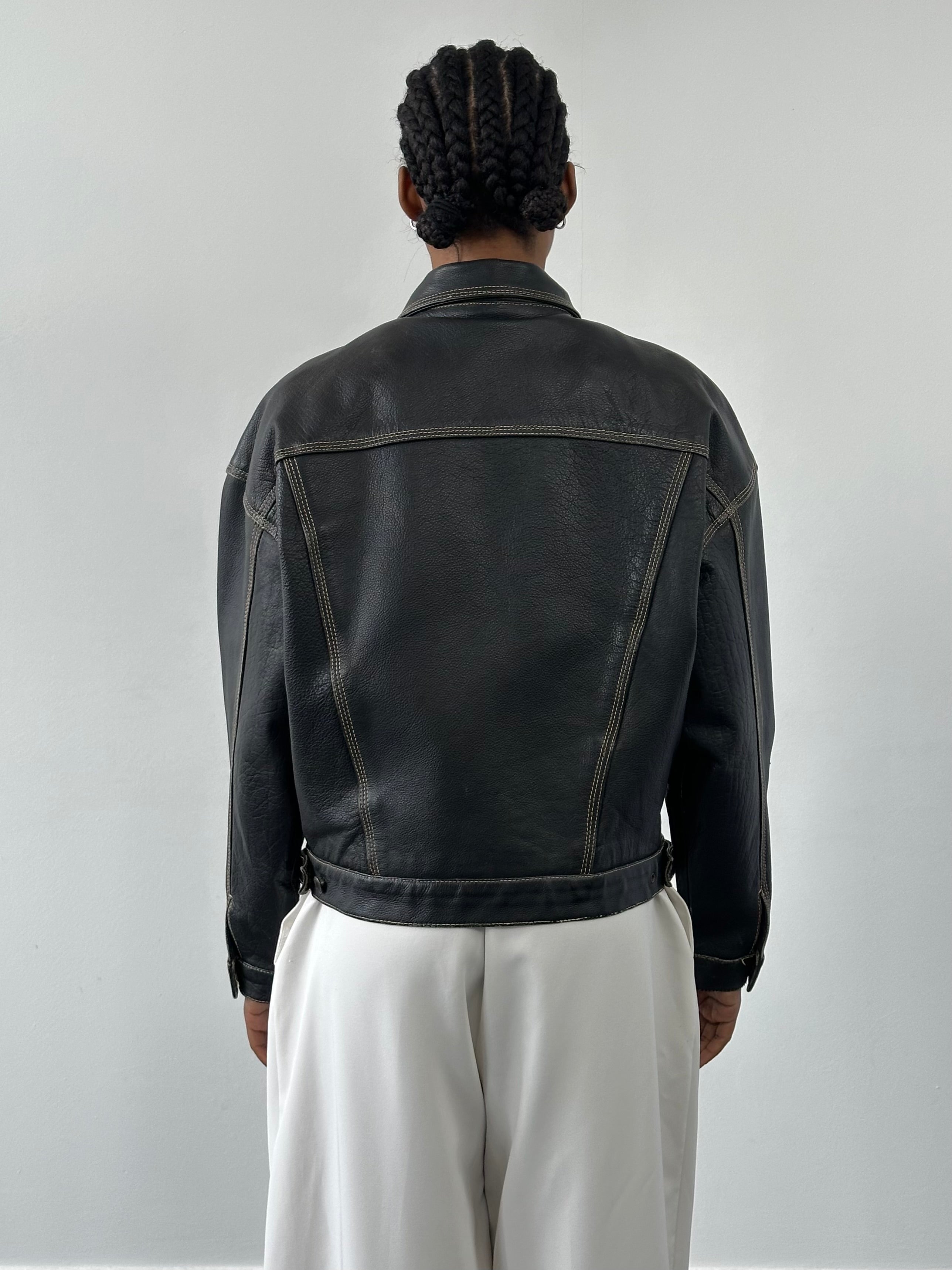Vintage 1990s leather boxy jacket in black, featuring a classic fit and textured leather, displayed on a hanger.