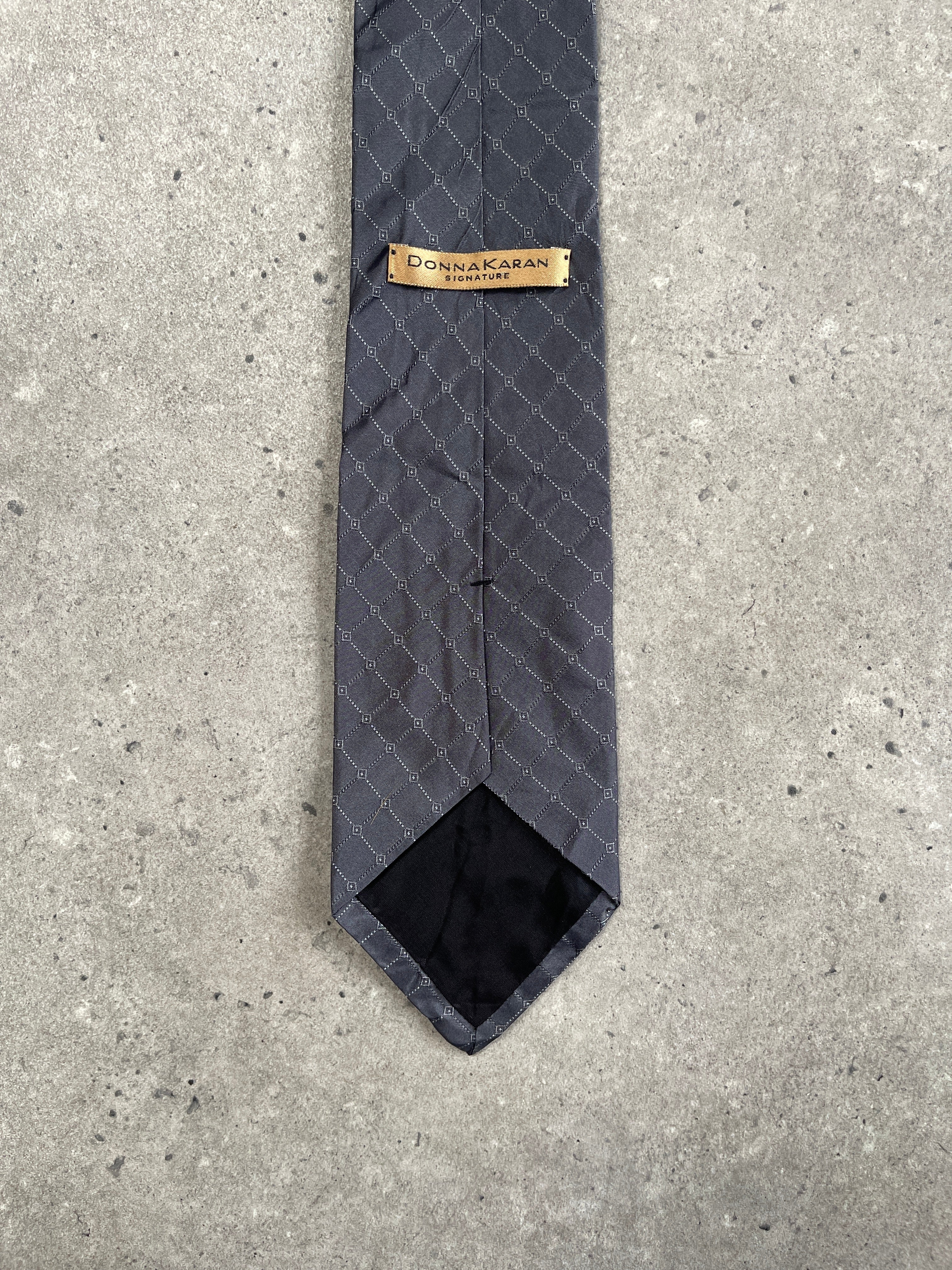 Donna Karan Signature 1990s pure silk print tie lying flat, showcasing vibrant patterns and elegant craftsmanship.