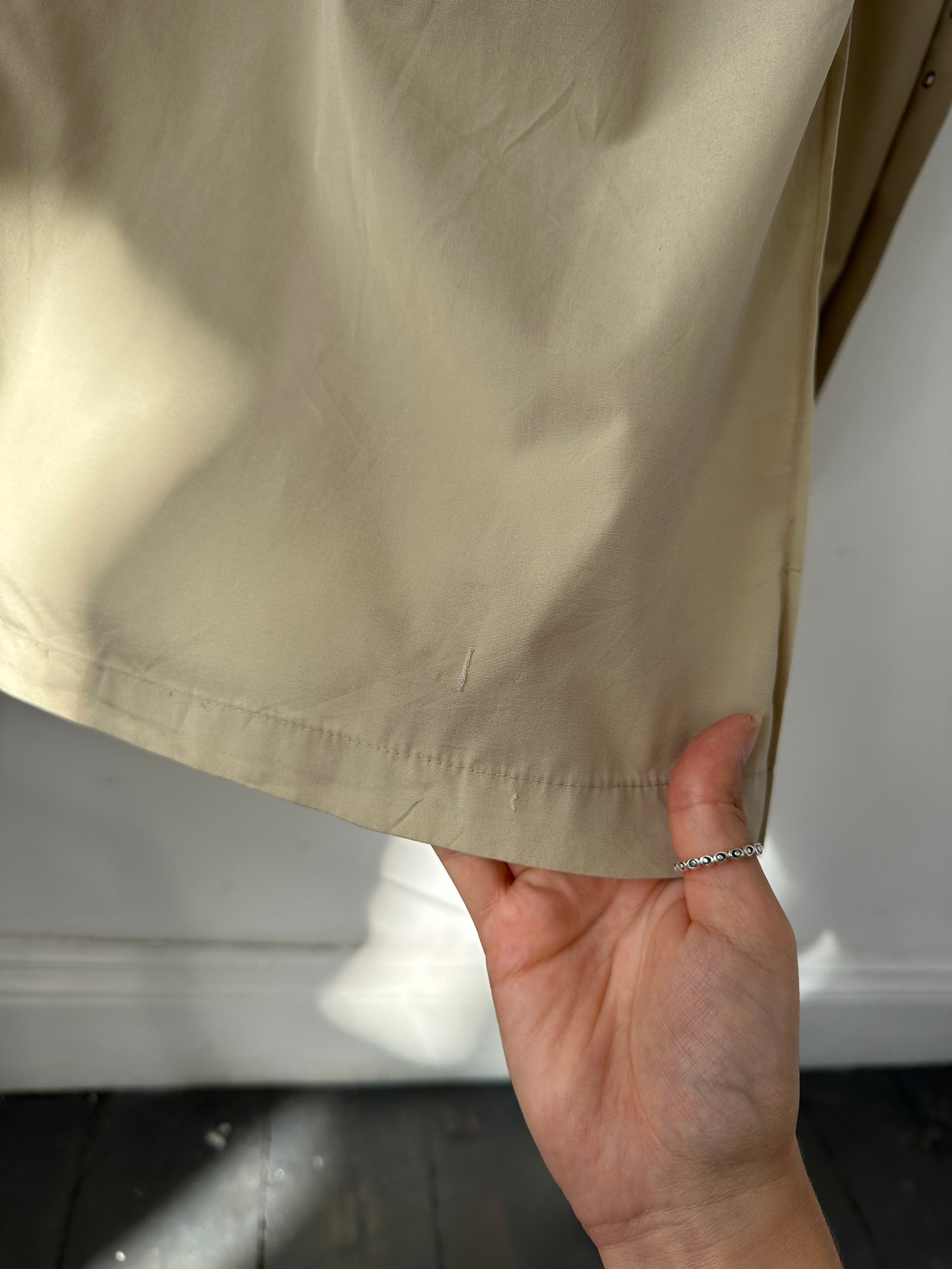 Christian Dior Paris cotton double-breasted belted trench coat in beige, displayed on a hanger with buttons and collar visible.