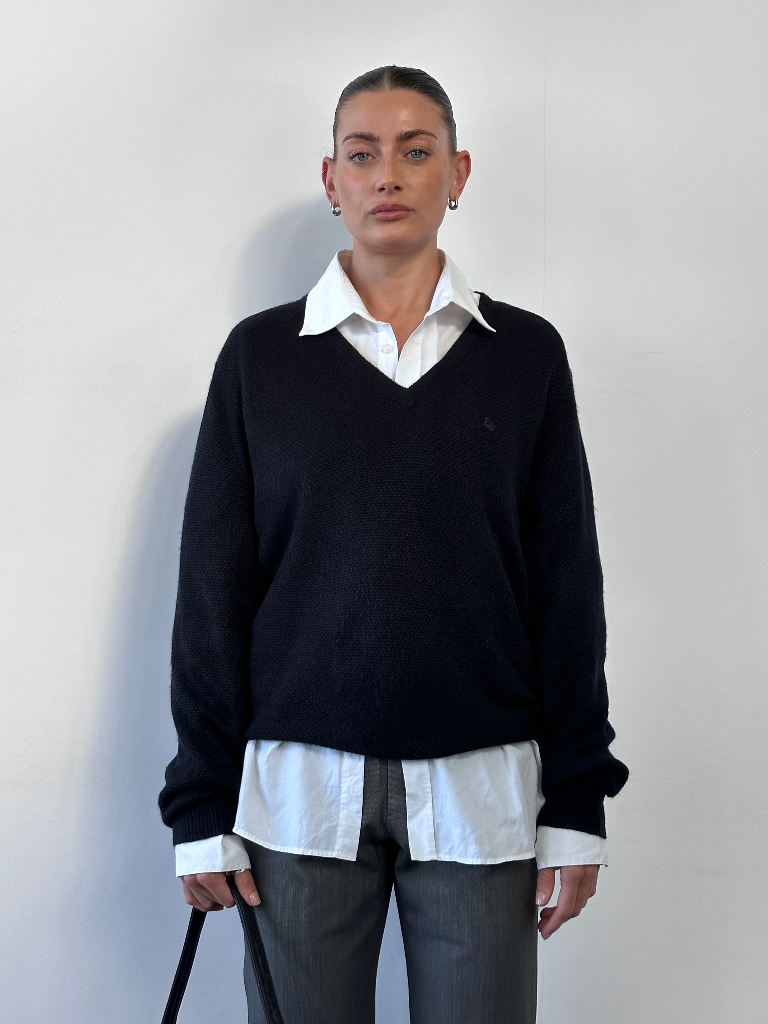 Christian Dior V neck logo knitted jumper in black, featuring a Dior emblem and ribbed cuffs, size M/L.