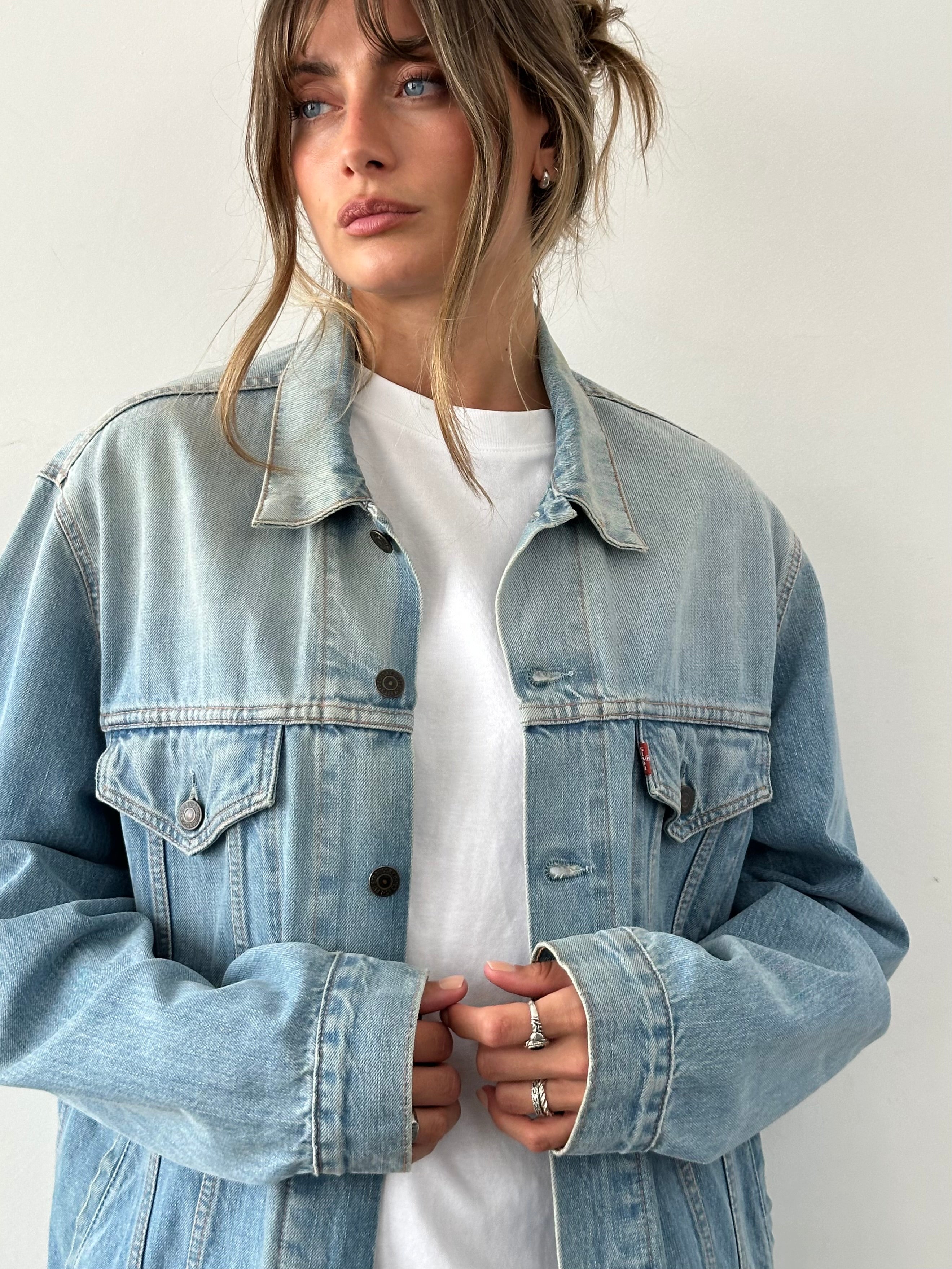 Levi’s faded denim jacket in size L, featuring classic design with distressed details and button closure.