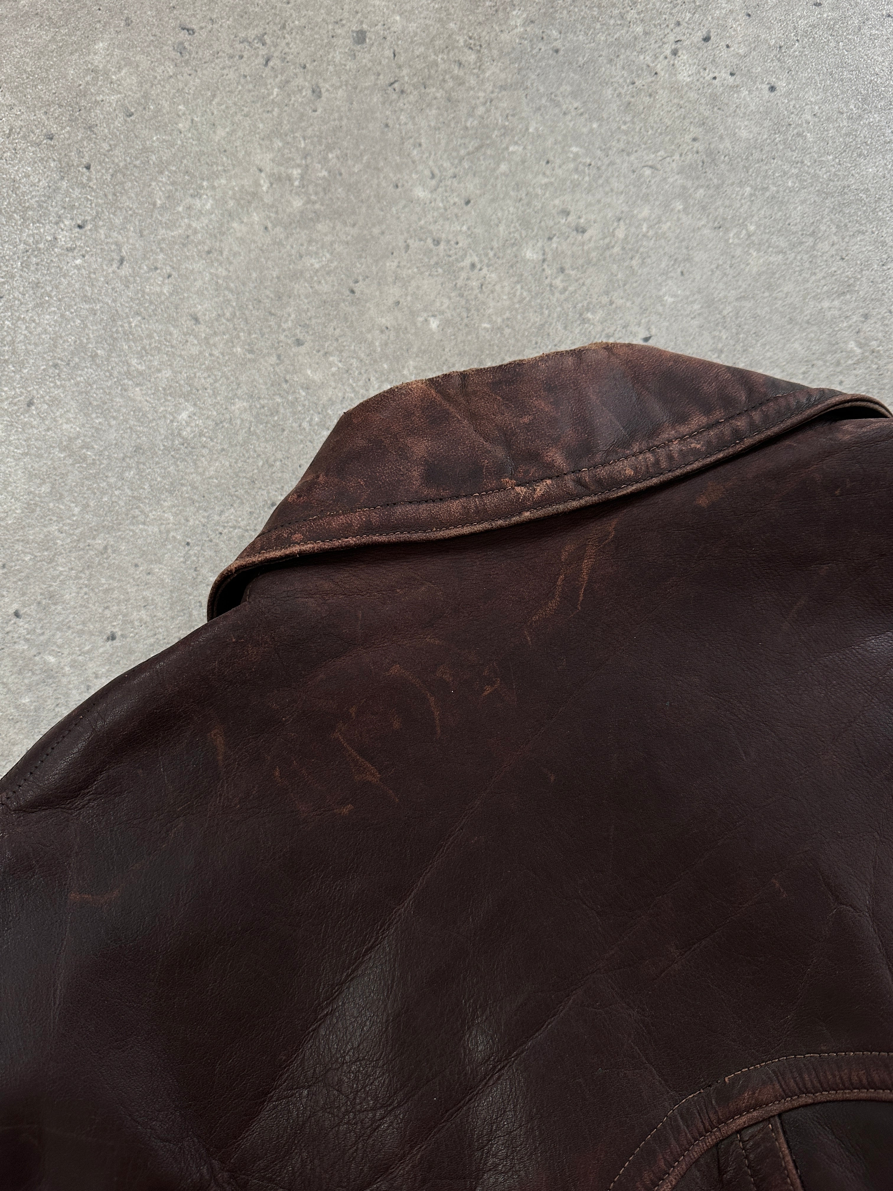 Vintage 1980s distressed leather biker jacket in size L/XL, featuring rugged styling and classic hardware details.