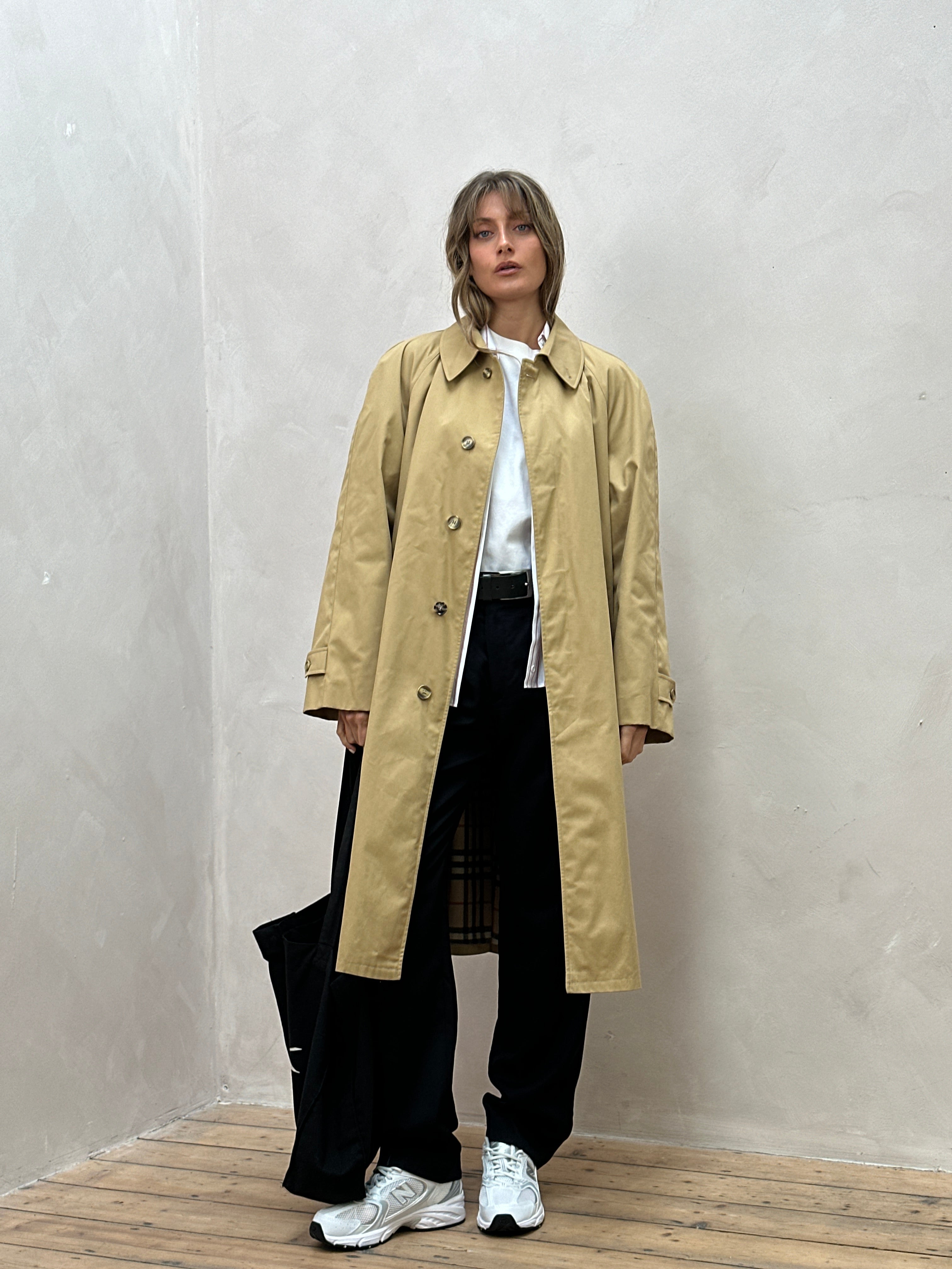 Vintage brand vintage trench coat with concealed placket, belt, and oversized fit, shown in classic beige fabric.