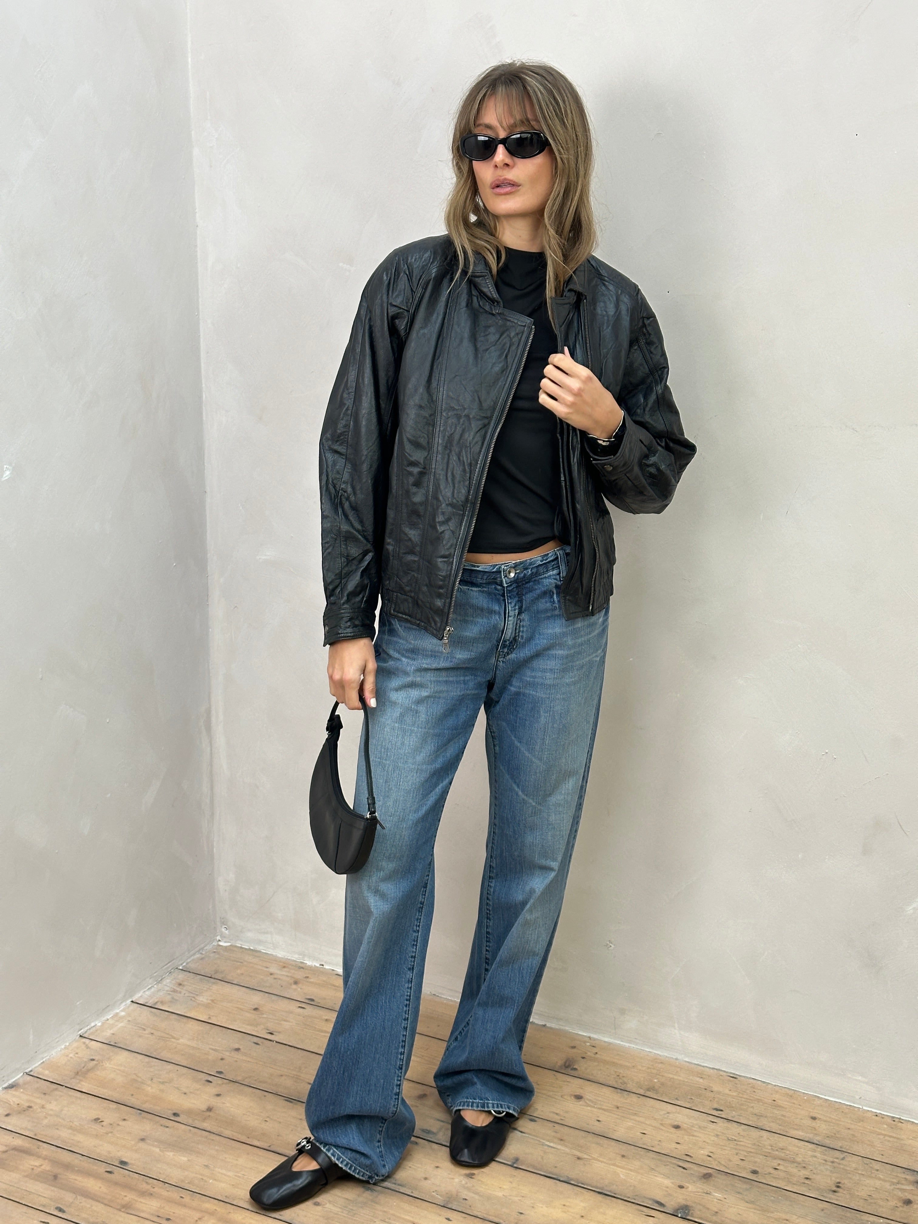Vintage leather biker jacket in size small/medium with classic styling and distressed finish, displayed on a hanger.