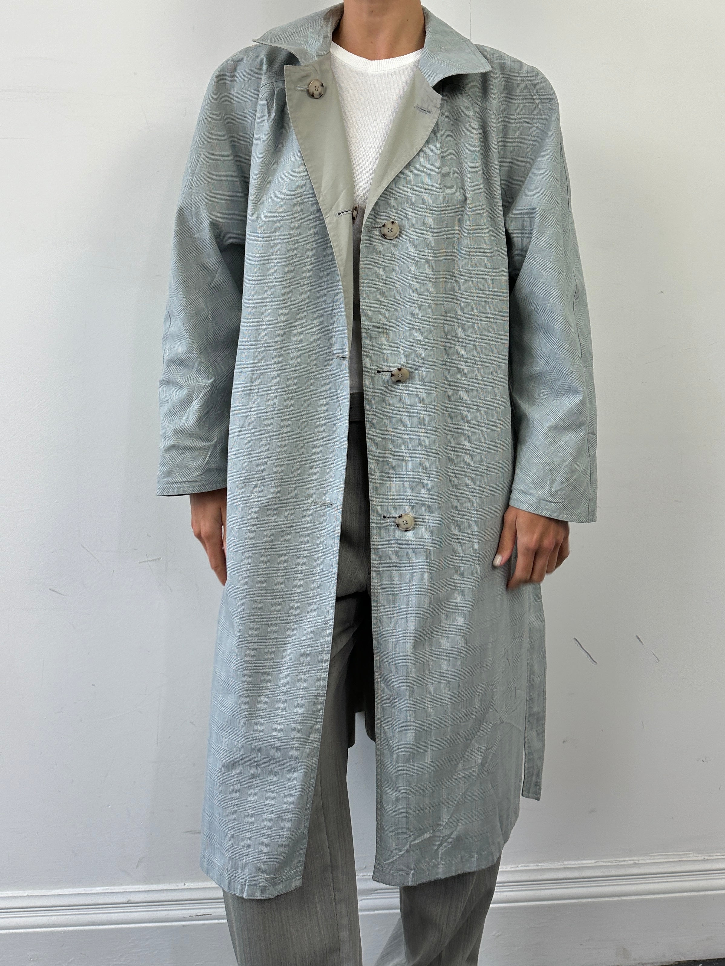 Vintage reversible trench coat in check pattern with belted design, showerproof and suitable for size L, shown hanging on a rack.