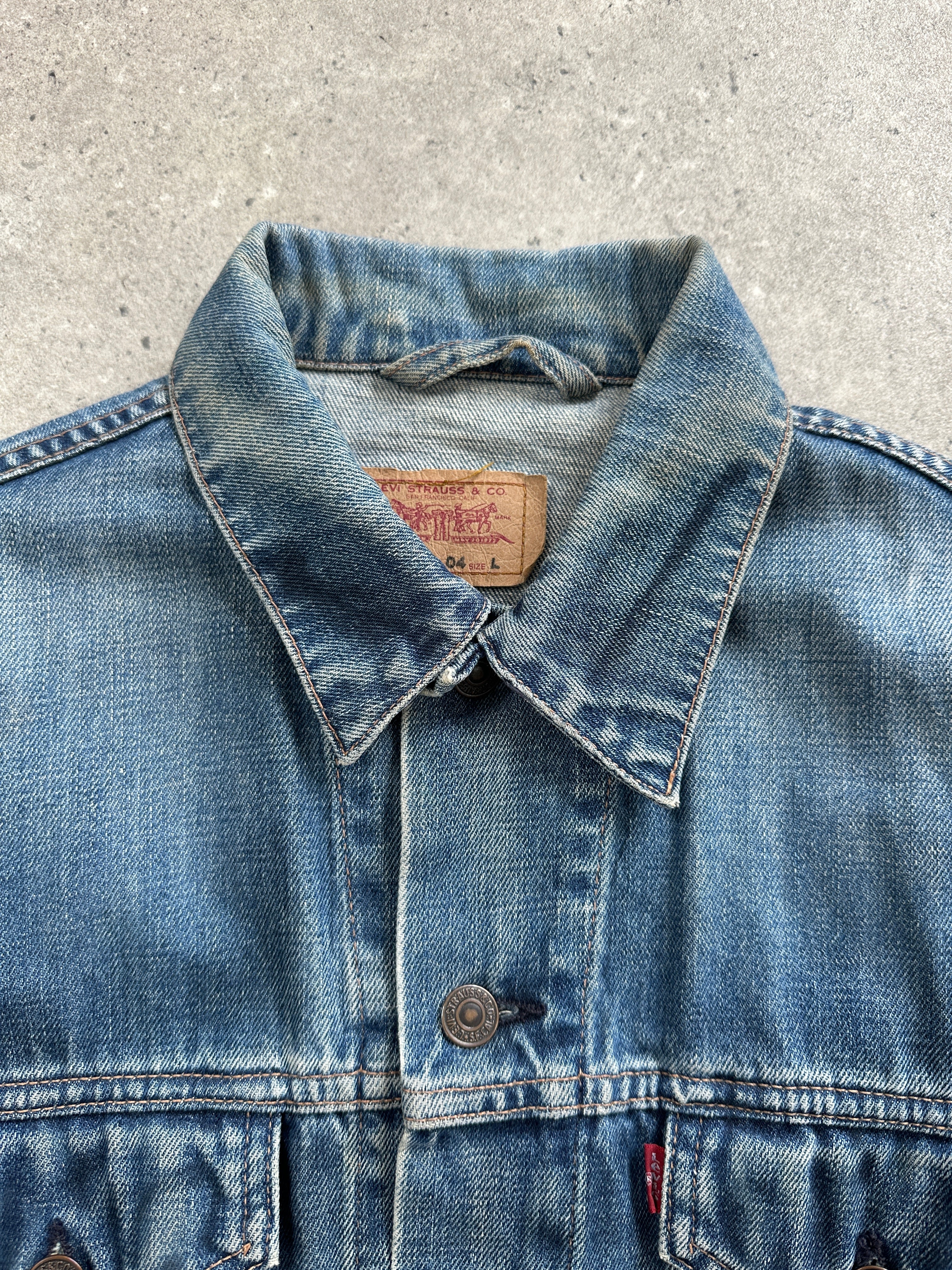 Levi’s 1990s faded denim jacket in medium size, featuring classic wash and vintage style, displayed on a hanger.
