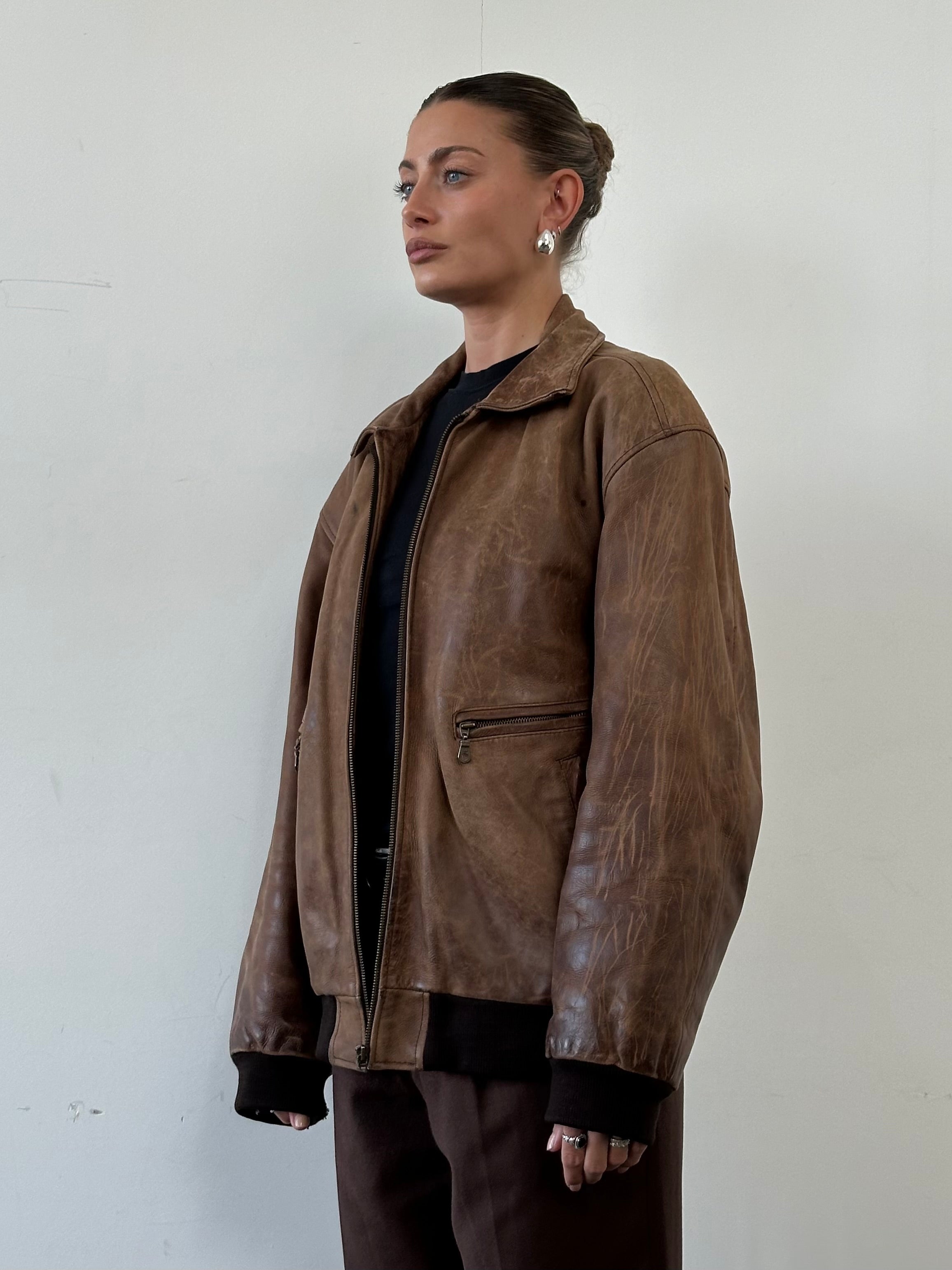 Vintage distressed leather bomber jacket in XL size, featuring rugged style and classic design, displayed on a neutral background.