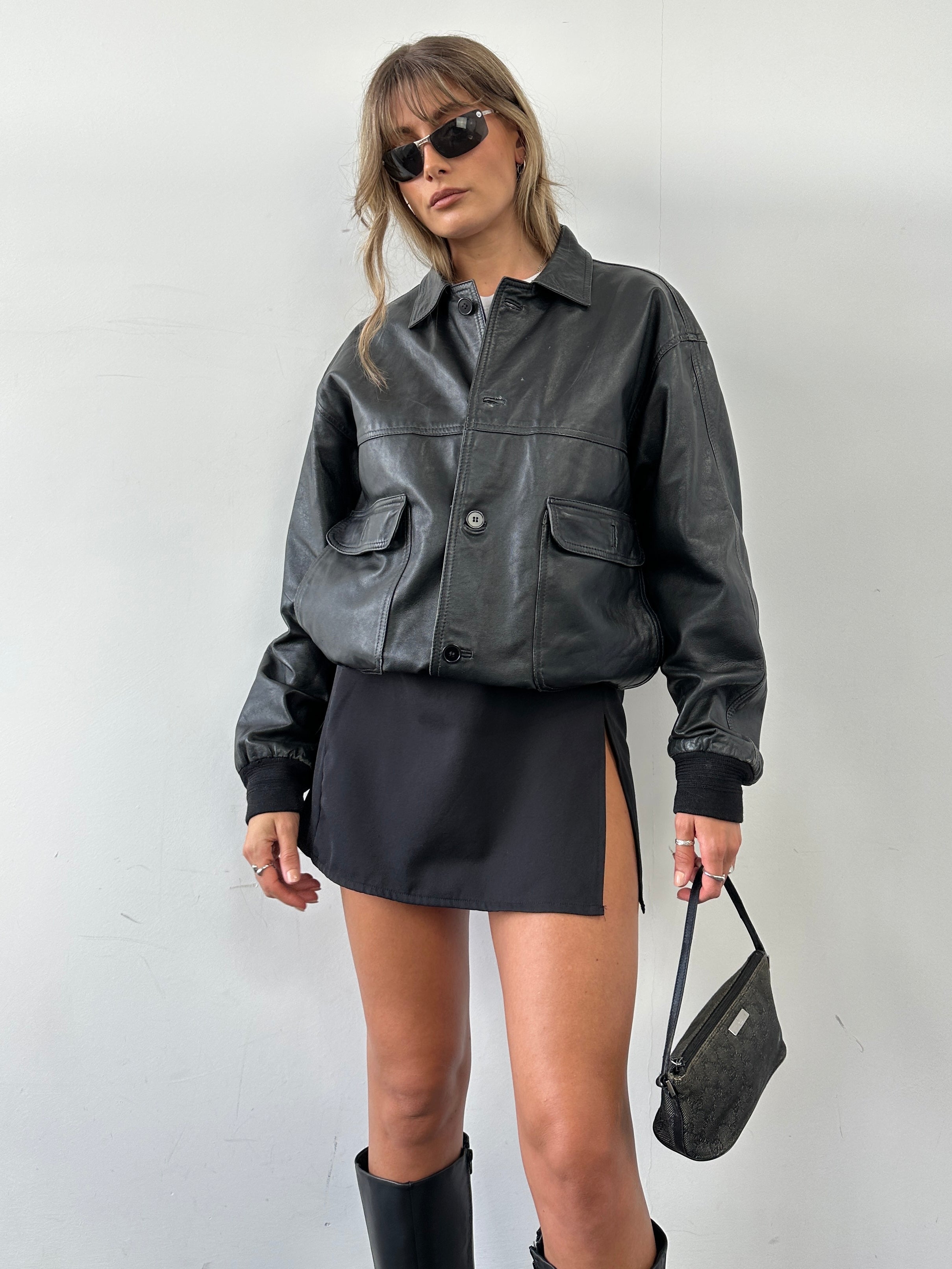 Vintage leather bomber jacket in size M, featuring classic design with ribbed cuffs and collar, displayed on a hanger.