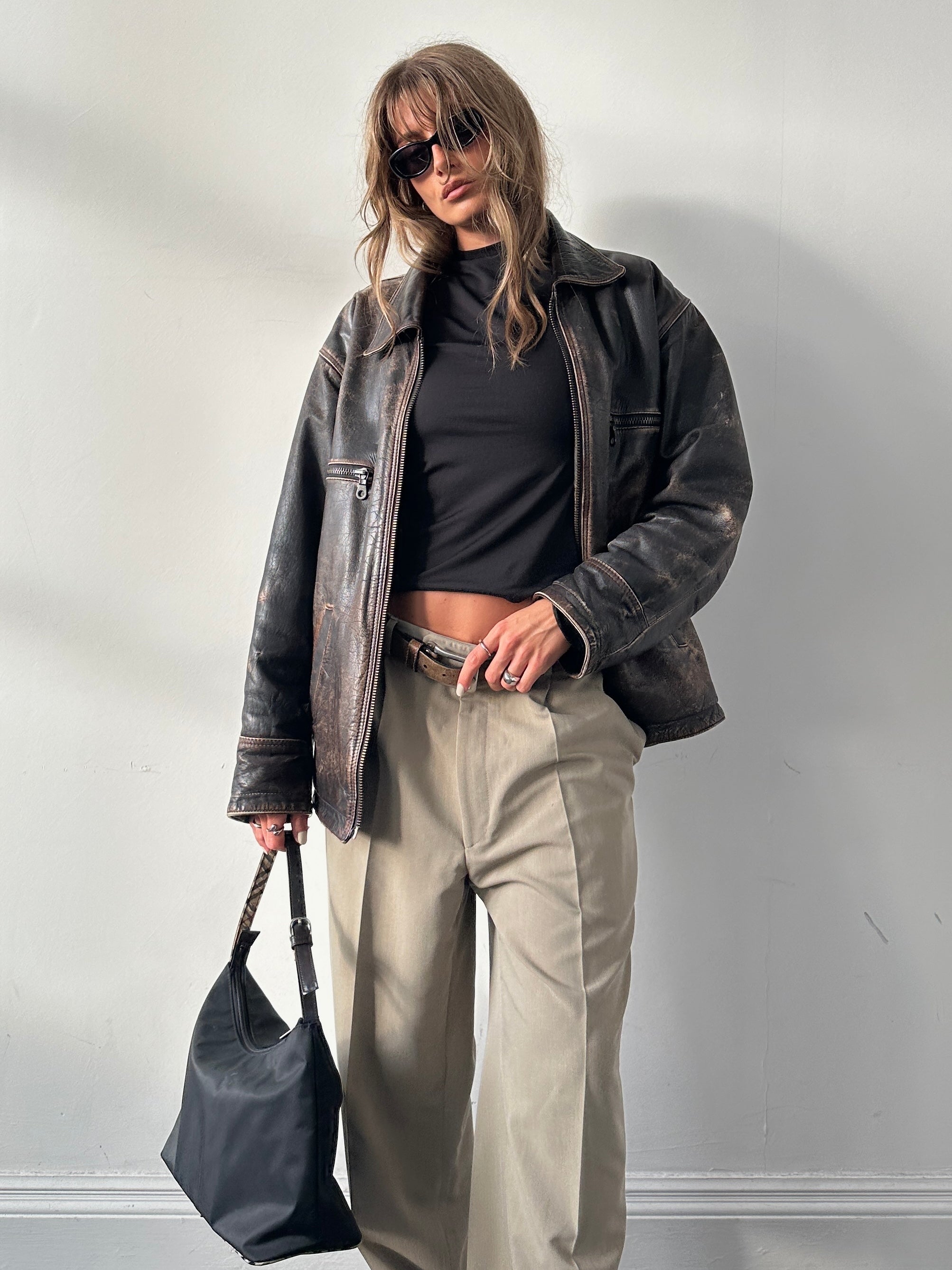 Vintage distressed leather jacket in M/L size, featuring rugged texture and classic style, displayed on a hanger.