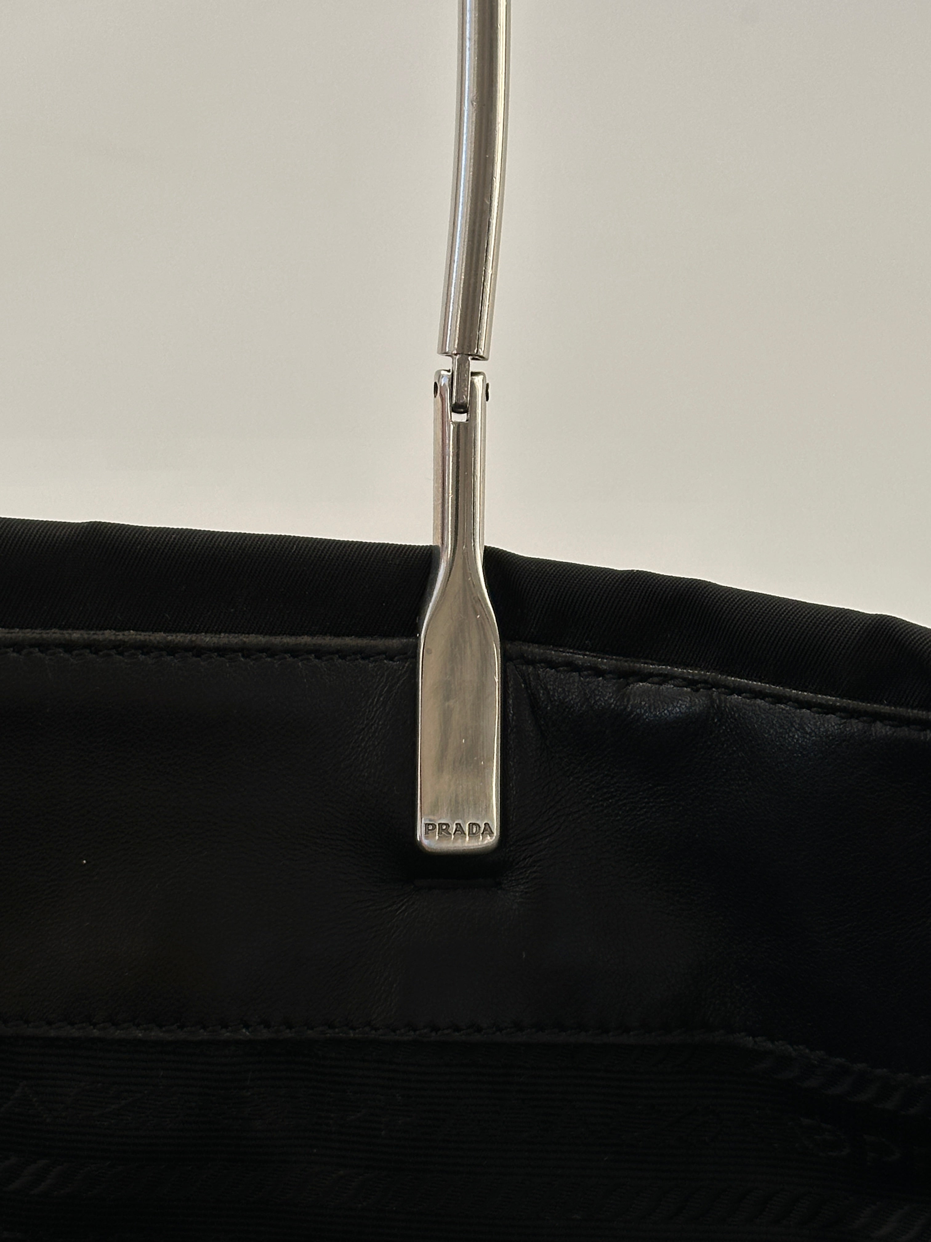 Prada nylon and leather tote bag with dual handles and spacious interior, featuring sleek design and subtle branding.