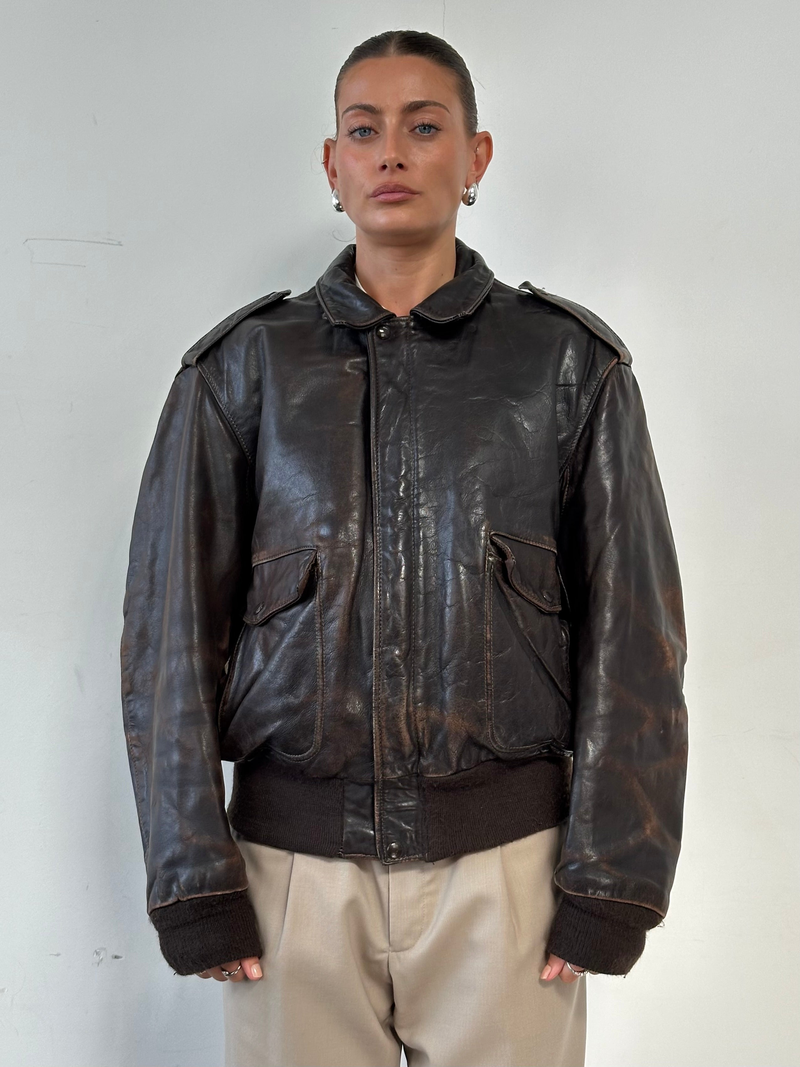 Schott NYC distressed leather bomber jacket in size L/XL, featuring a rugged, vintage look with detailed stitching and classic collar.