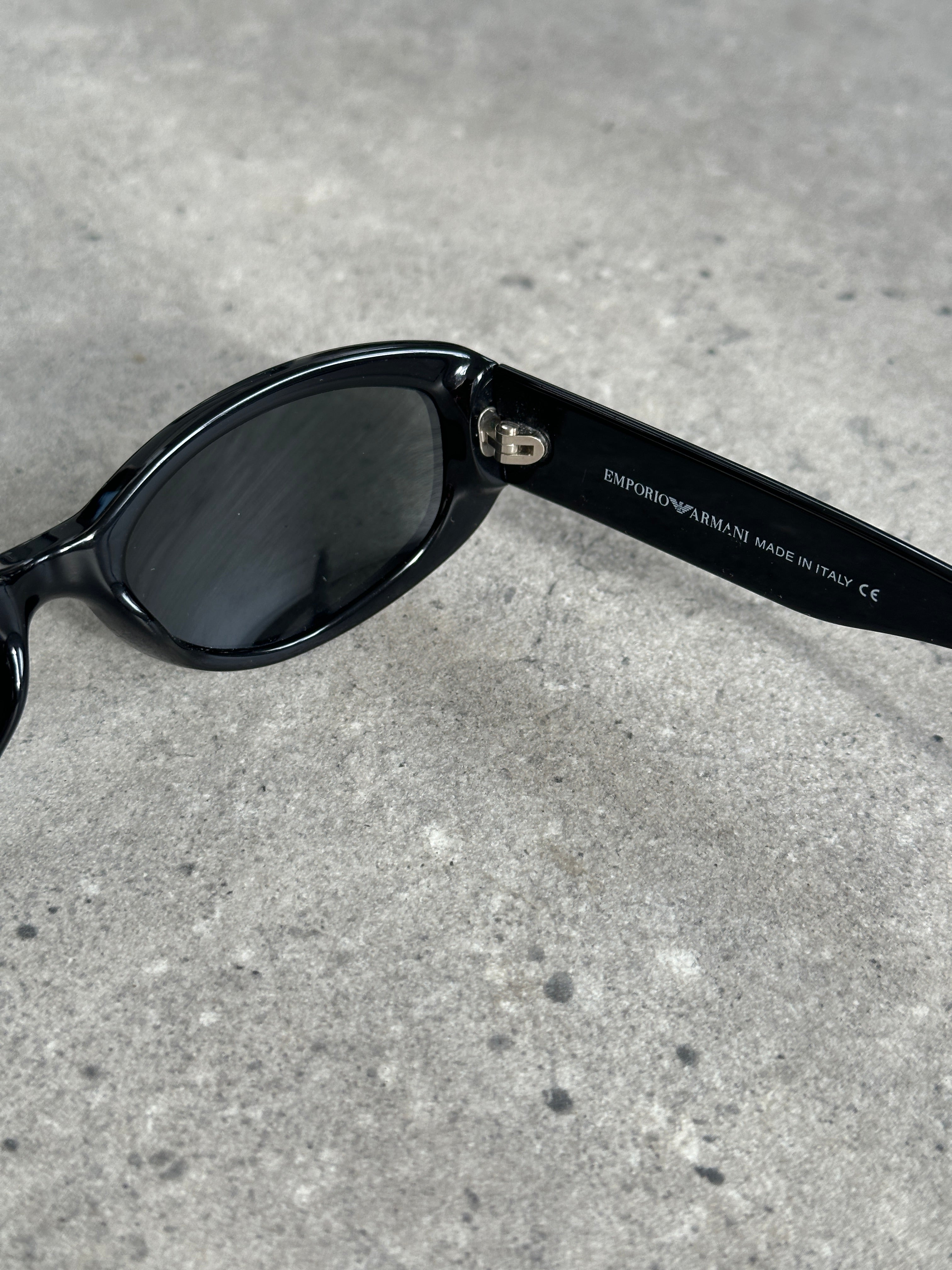 Emporio Armani oval sunglasses with dark tinted lenses and sleek black frames, stylish and modern accessory.