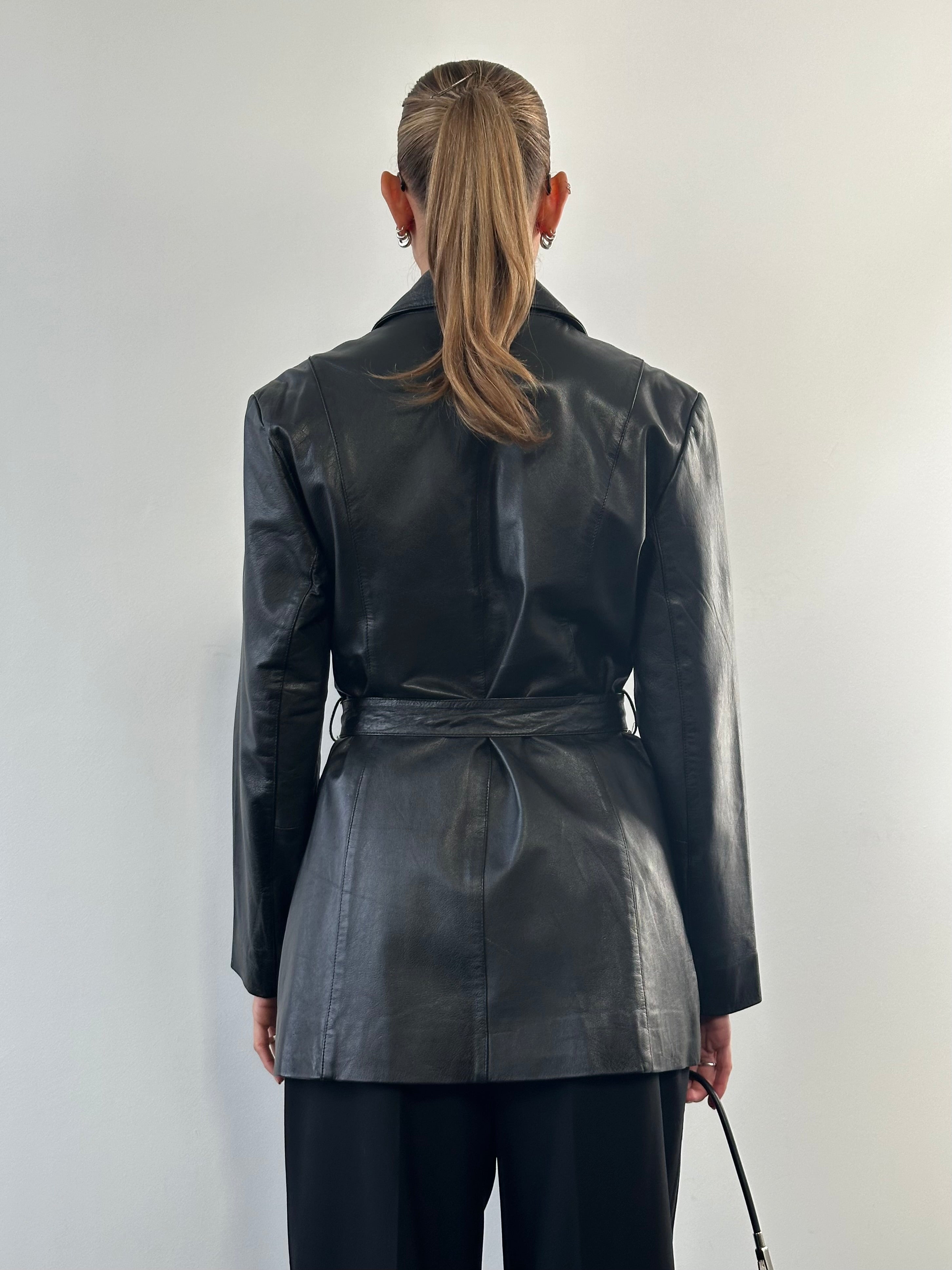 Vintage leather belted jacket in size M/L, featuring classic design and detailed stitching, displayed on a hanger.