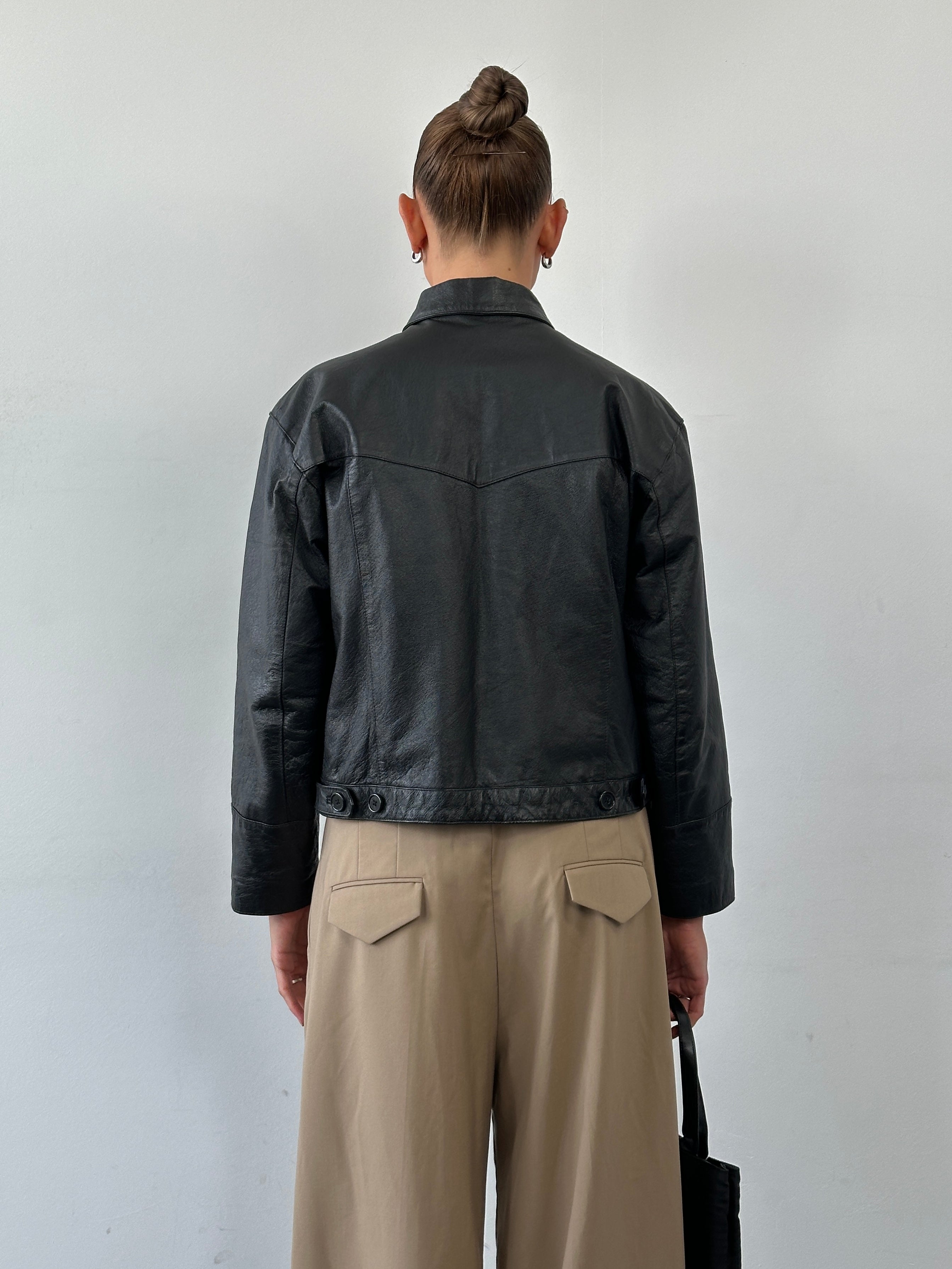 Vintage cropped leather jacket in size S, featuring classic design and textured leather, displayed on a neutral background.