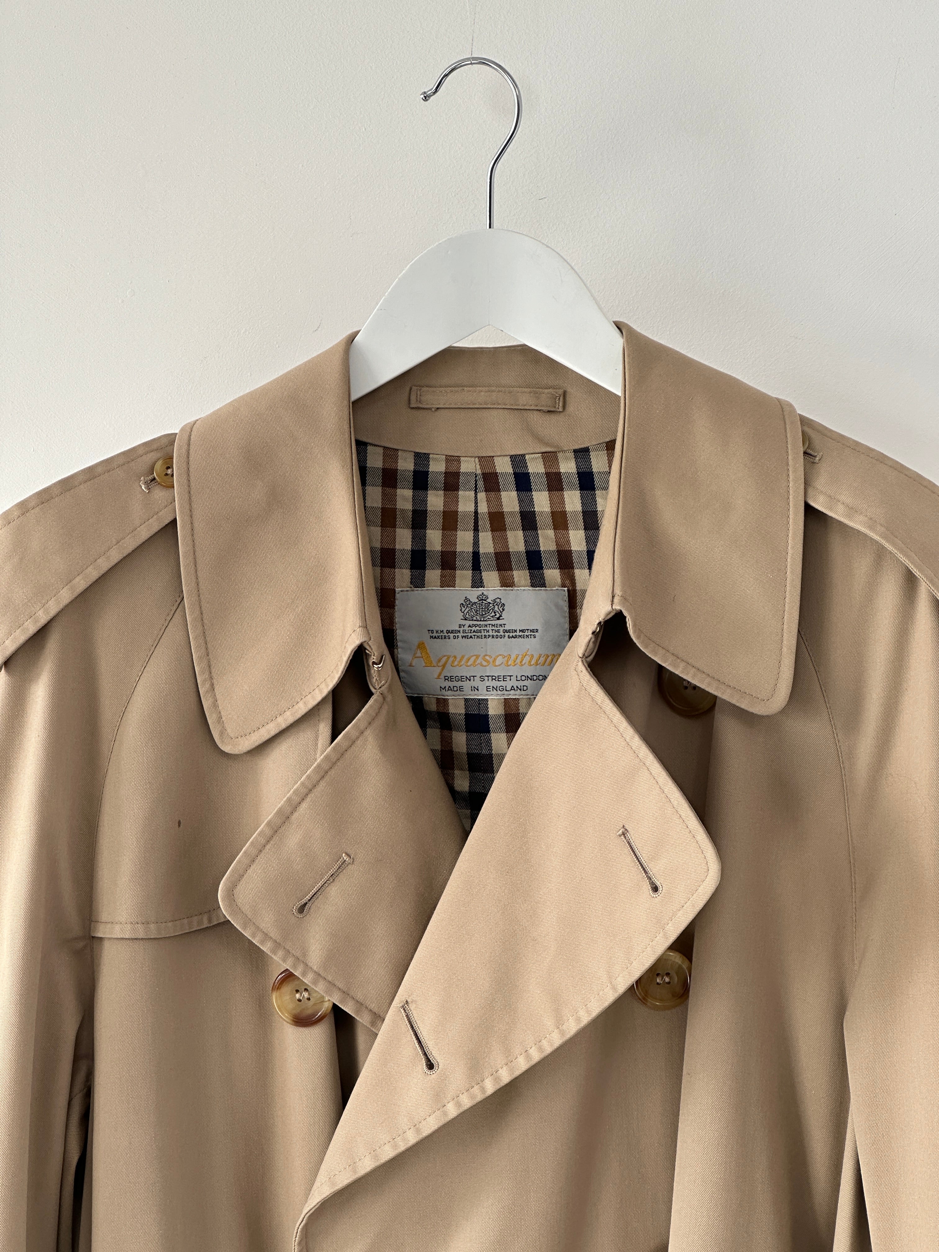Aquascutum cotton double-breasted belted trench coat in XL, showing the beige coat with classic lapels and belt detail.