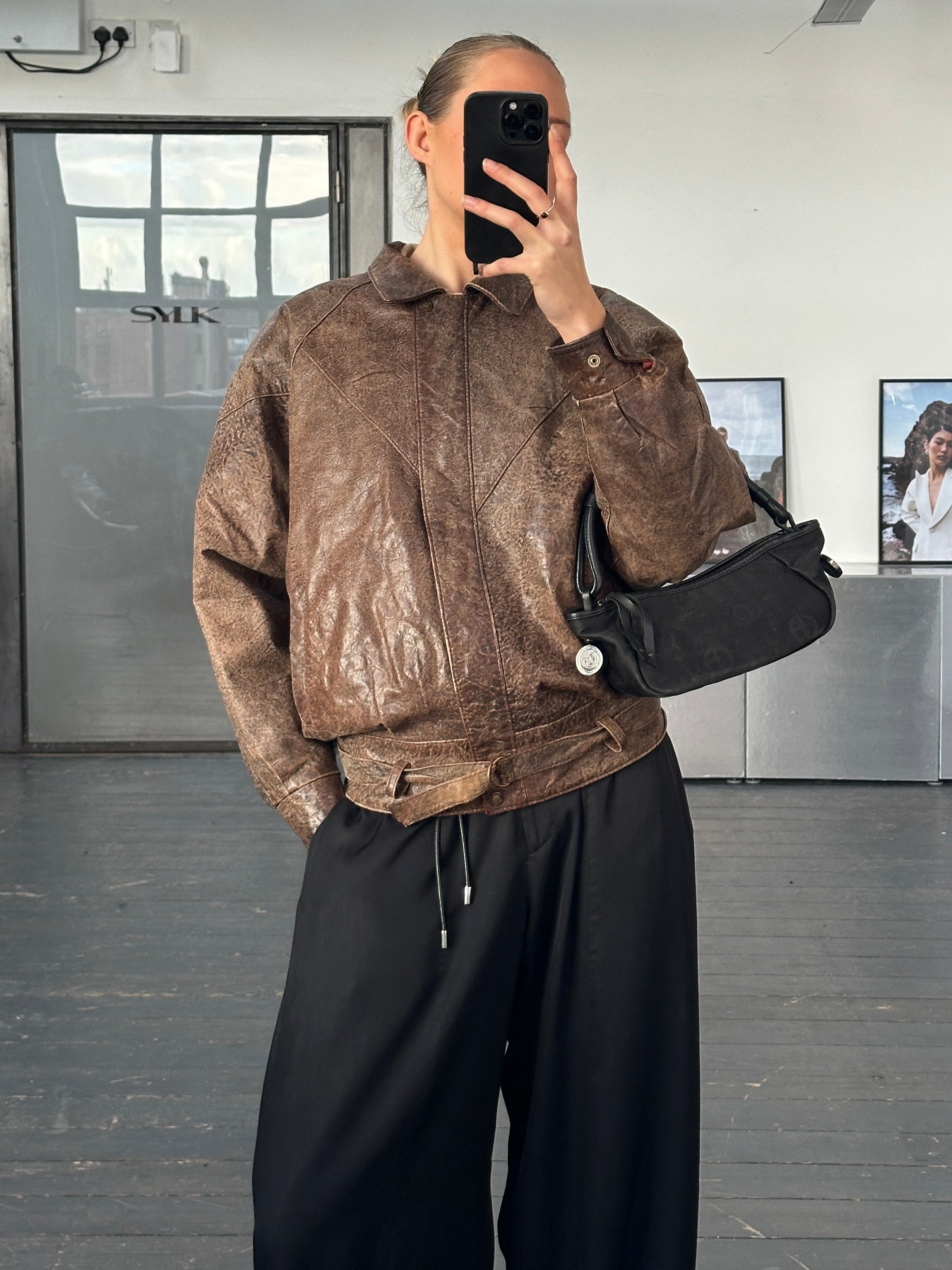 Vintage brand vintage 1980s aged leather jacket, size small, showing distressed brown leather with classic collar and front zipper.