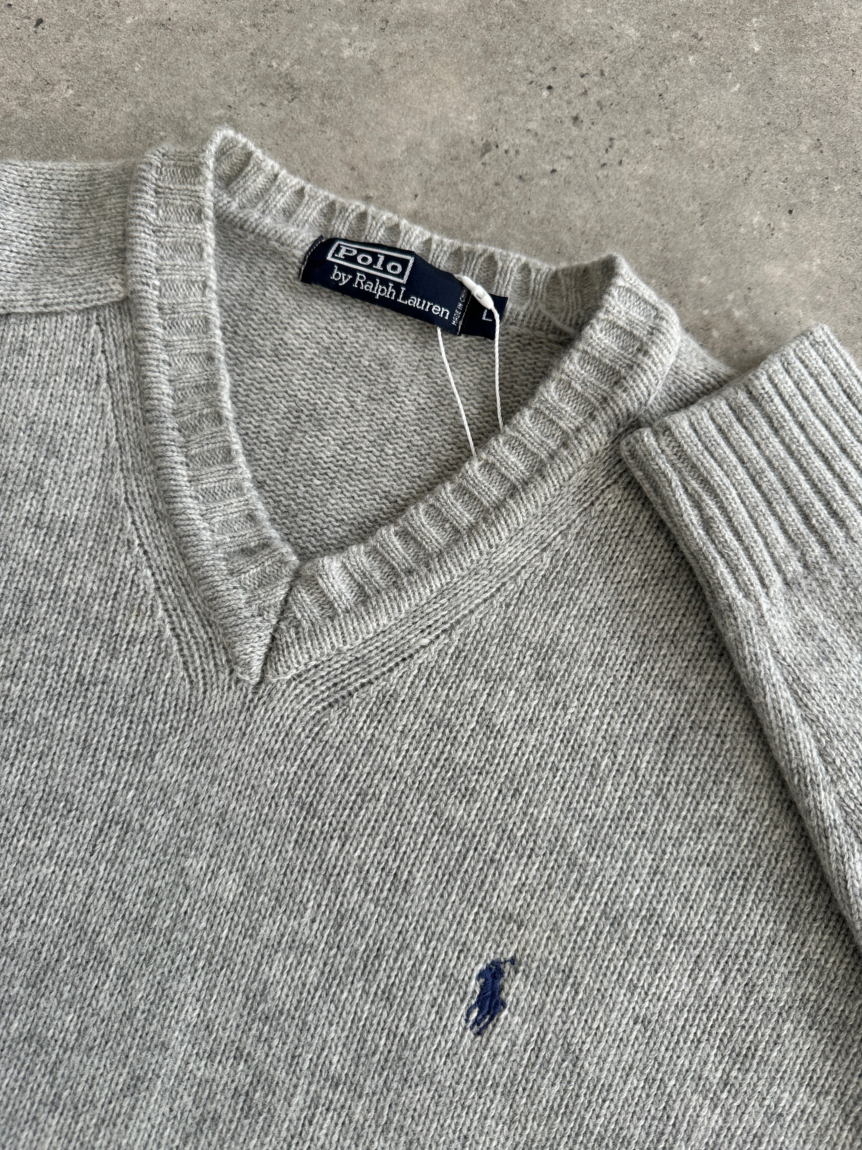 Ralph Lauren XL wool V-neck jumper in navy, featuring classic knit pattern and ribbed cuffs, displayed on a plain background.