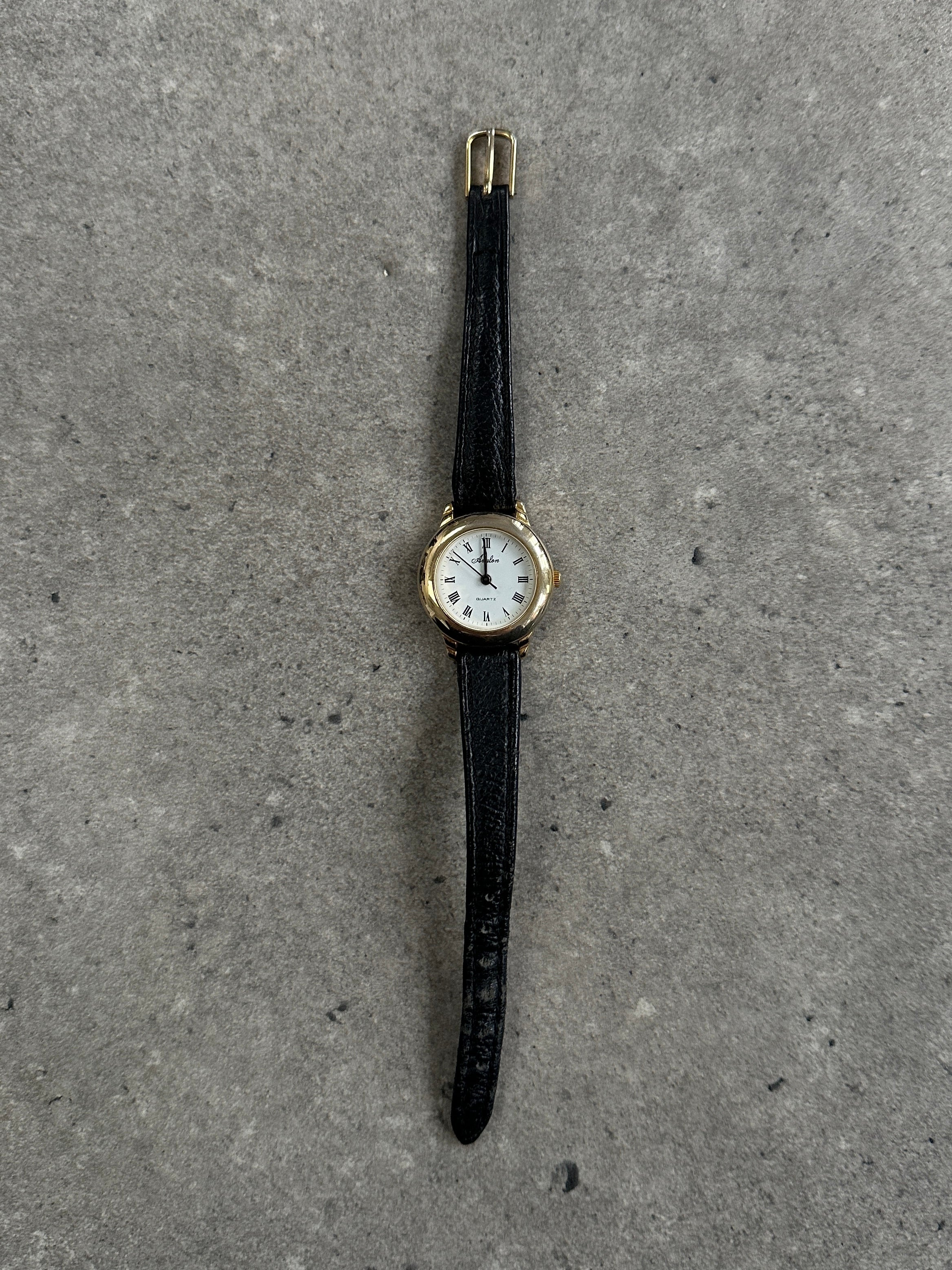 Vintage 1990s gold tone round quartz watch with classic design and metal band, featuring a minimalist dial and vintage charm.