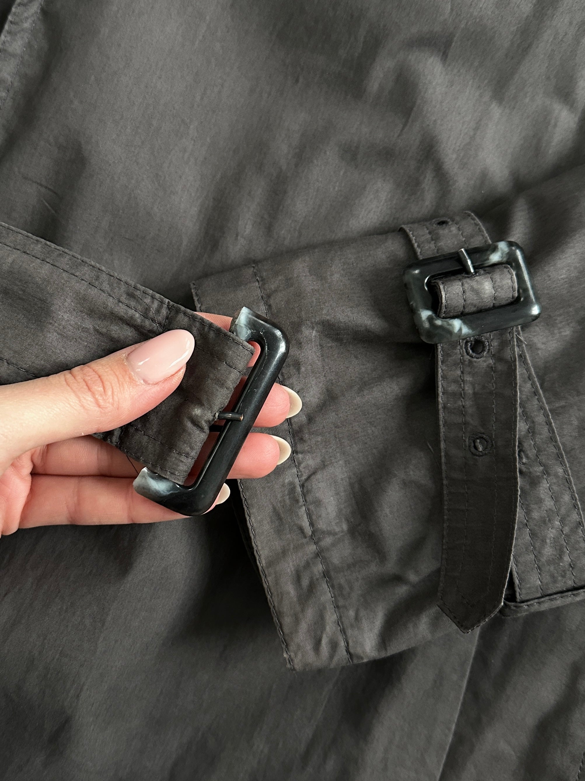 Vintage double-breasted unlined belted trench coat in size L, featuring classic design and neutral fabric, displayed on a hanger.