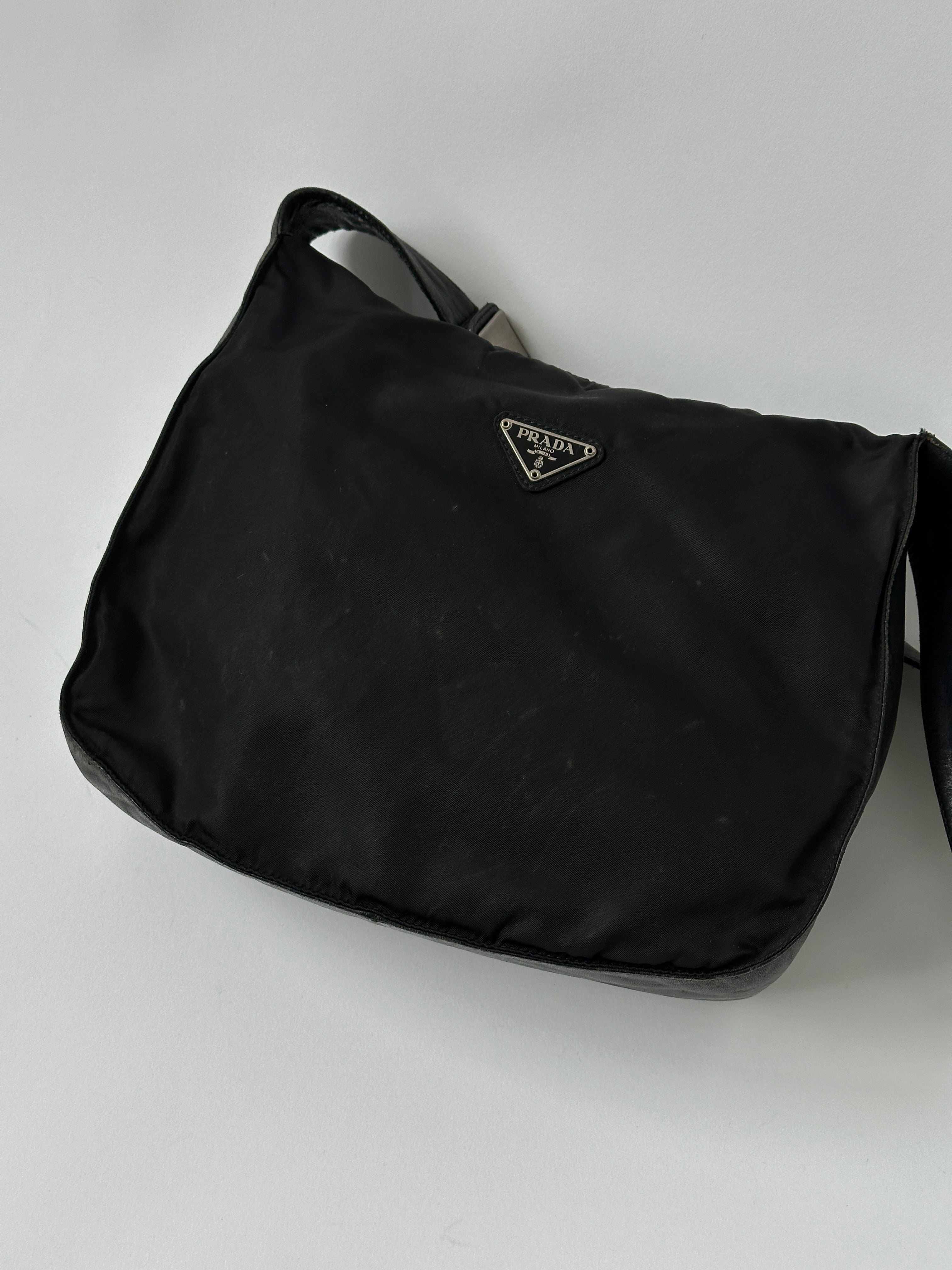 Prada nylon and leather crossbody bag with adjustable strap and sleek design, shown in a close-up view.