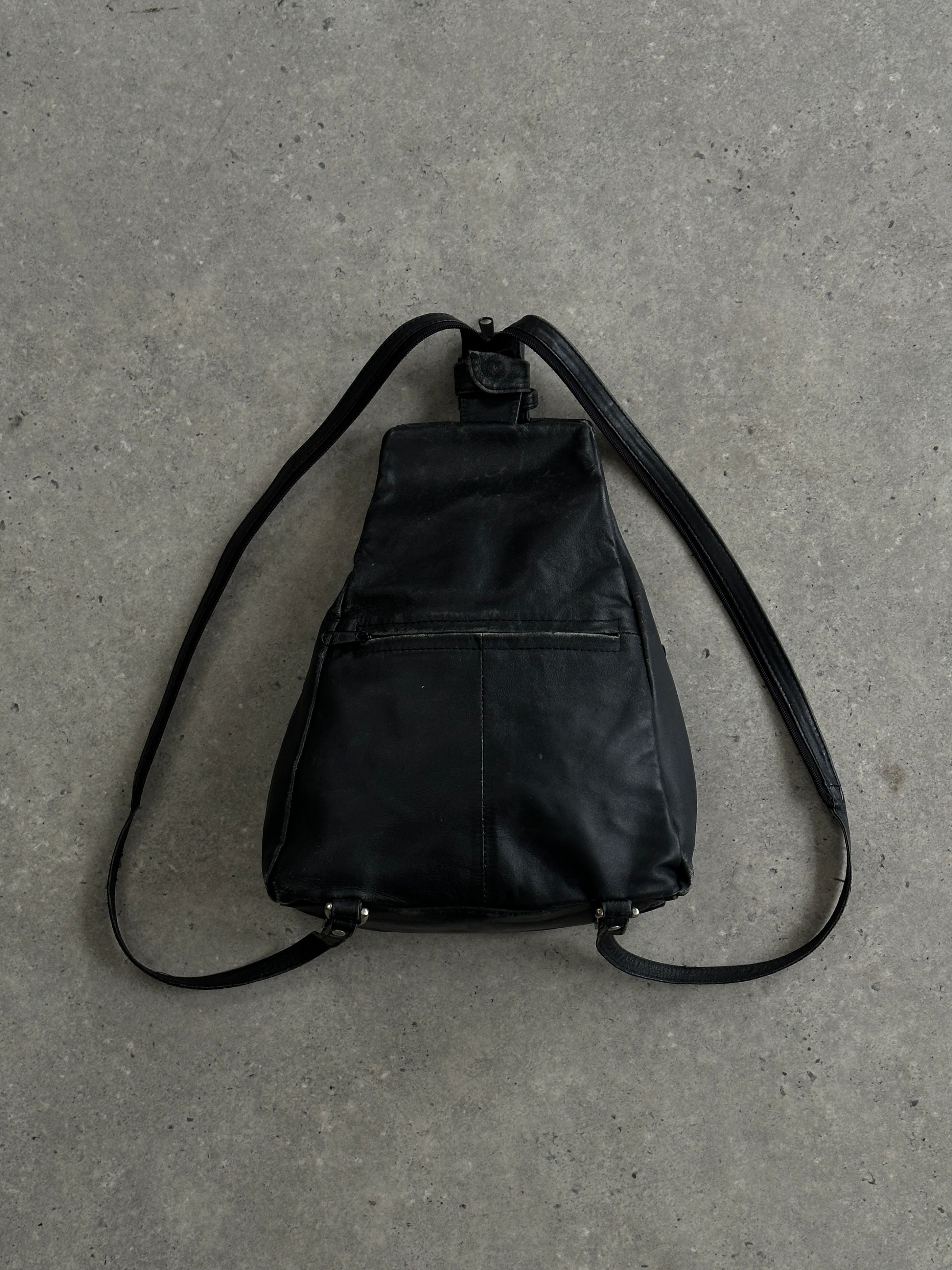 Vintage distressed faux leather rucksack crossbody bag with adjustable strap and vintage-style hardware, worn for casual outings.