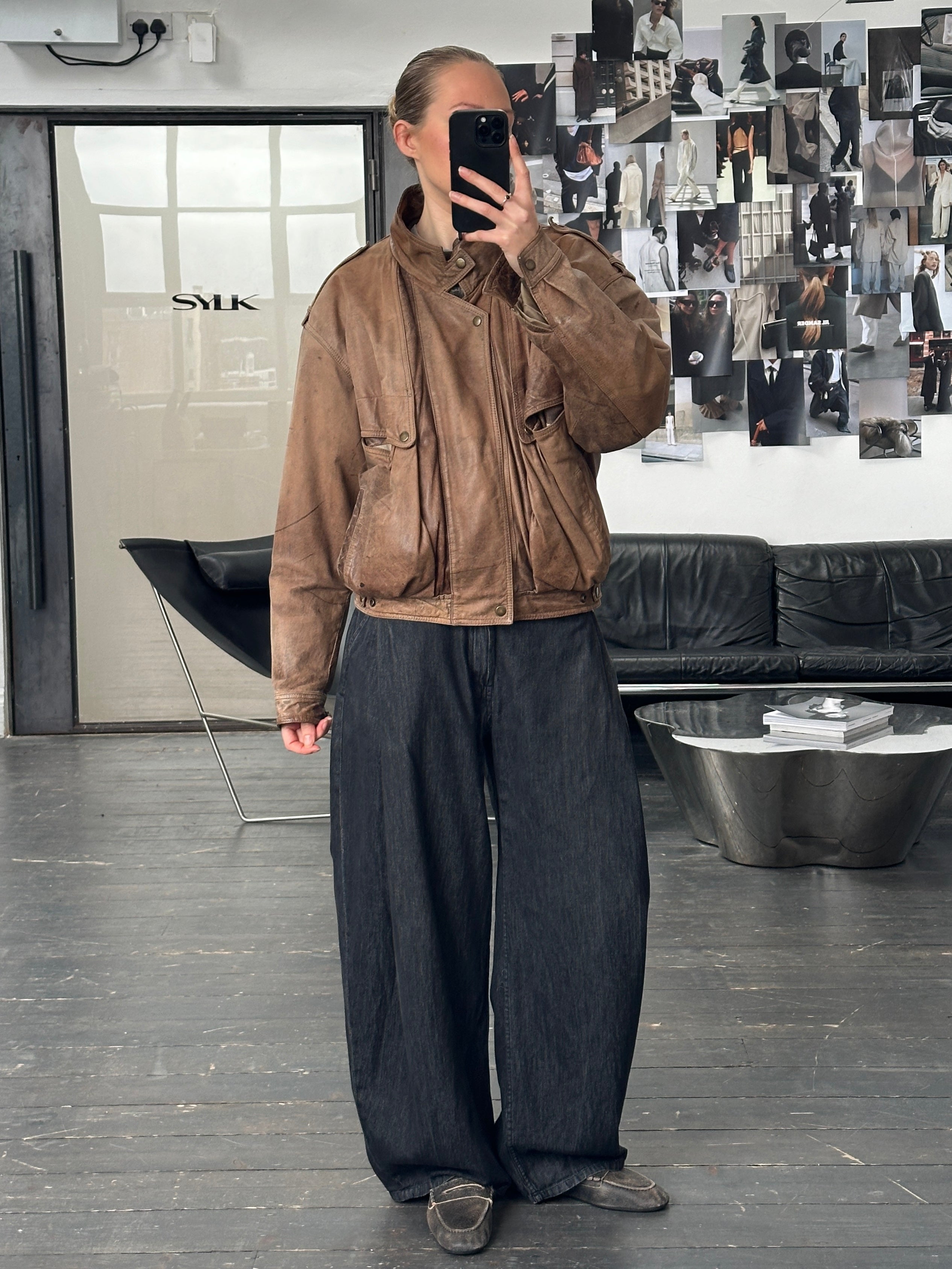 Vintage 1990s high neck leather bomber jacket in aged leather, displayed on a hanger, with a classic vintage style.