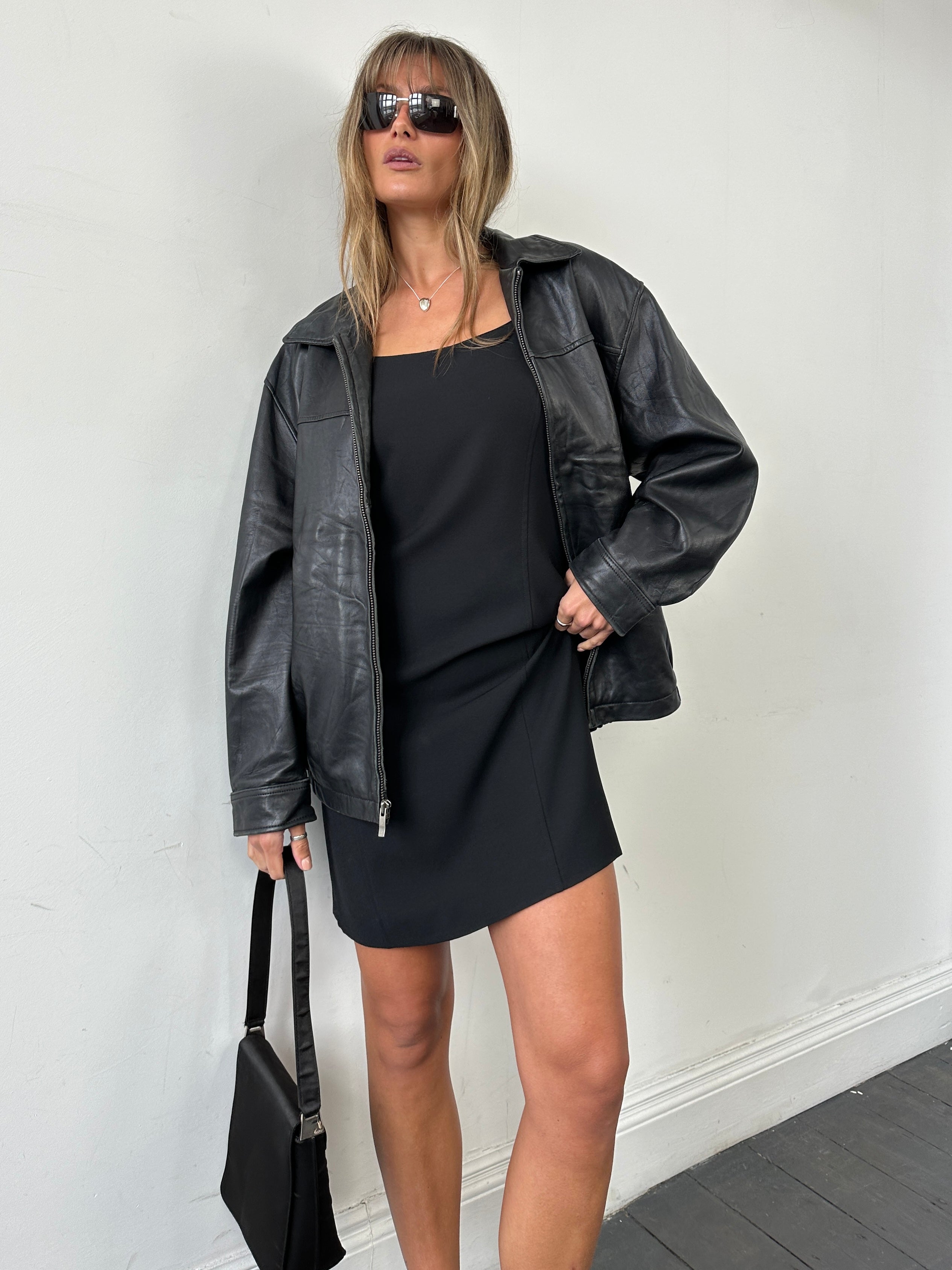 Vintage minimal leather jacket in size L/XL hanging on a hanger, showcasing sleek design and classic style.