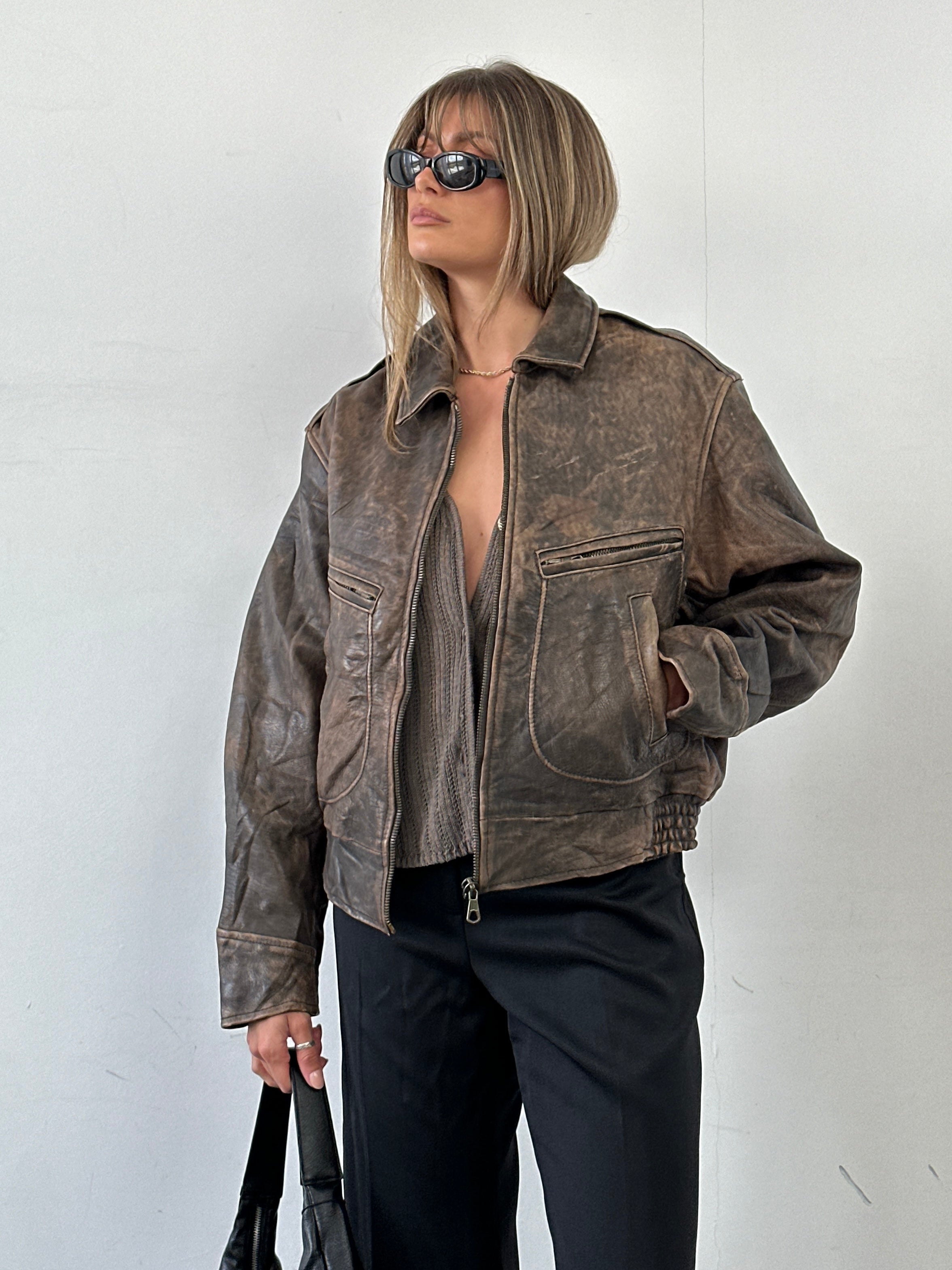 Vintage distressed leather bomber jacket in M/L size, featuring a rugged, worn-in look with classic style and durable leather material.