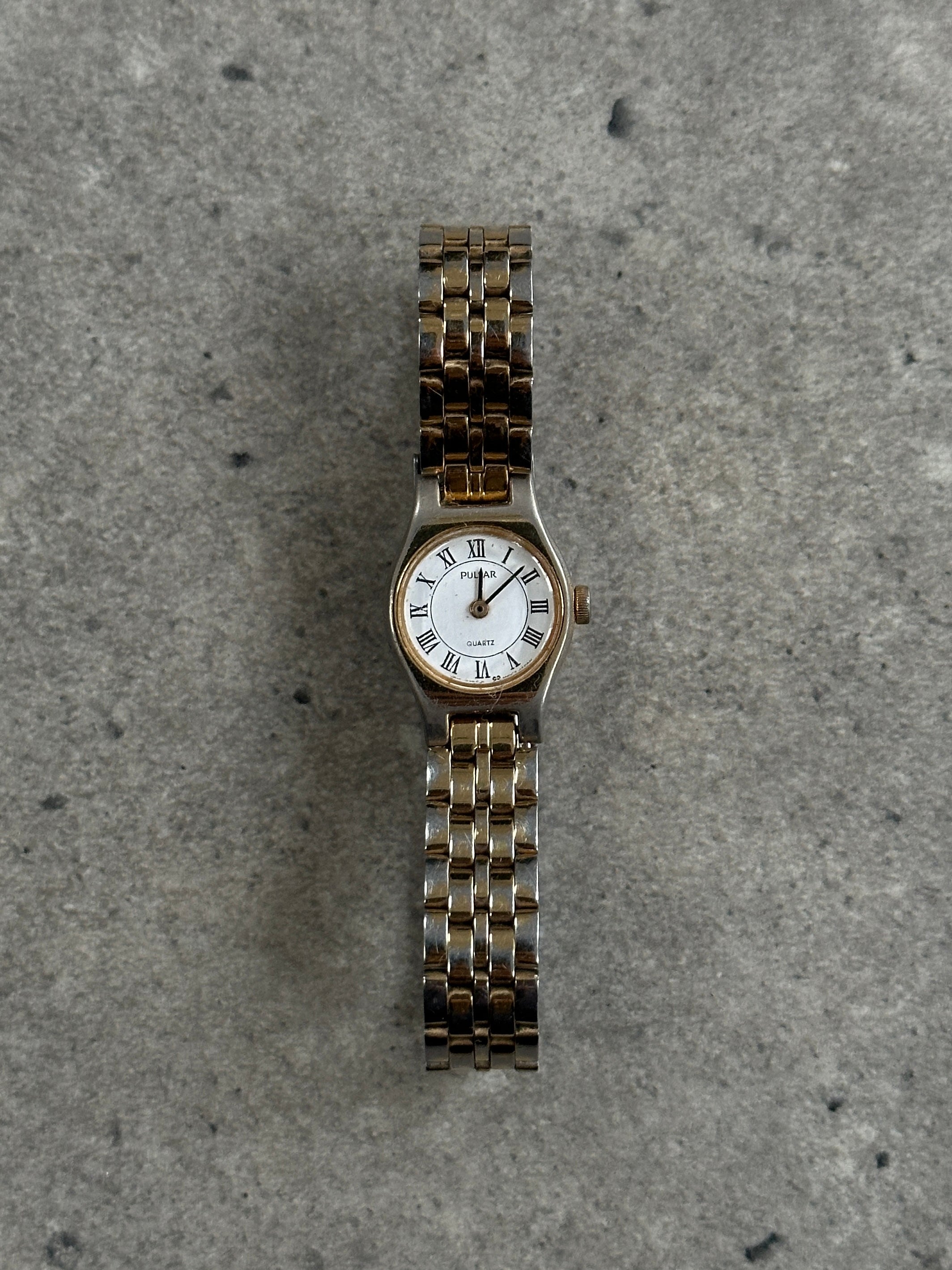 Pulsar 1990s two-tone round quartz watch with silver and gold accents, featuring a classic dial and sleek design.