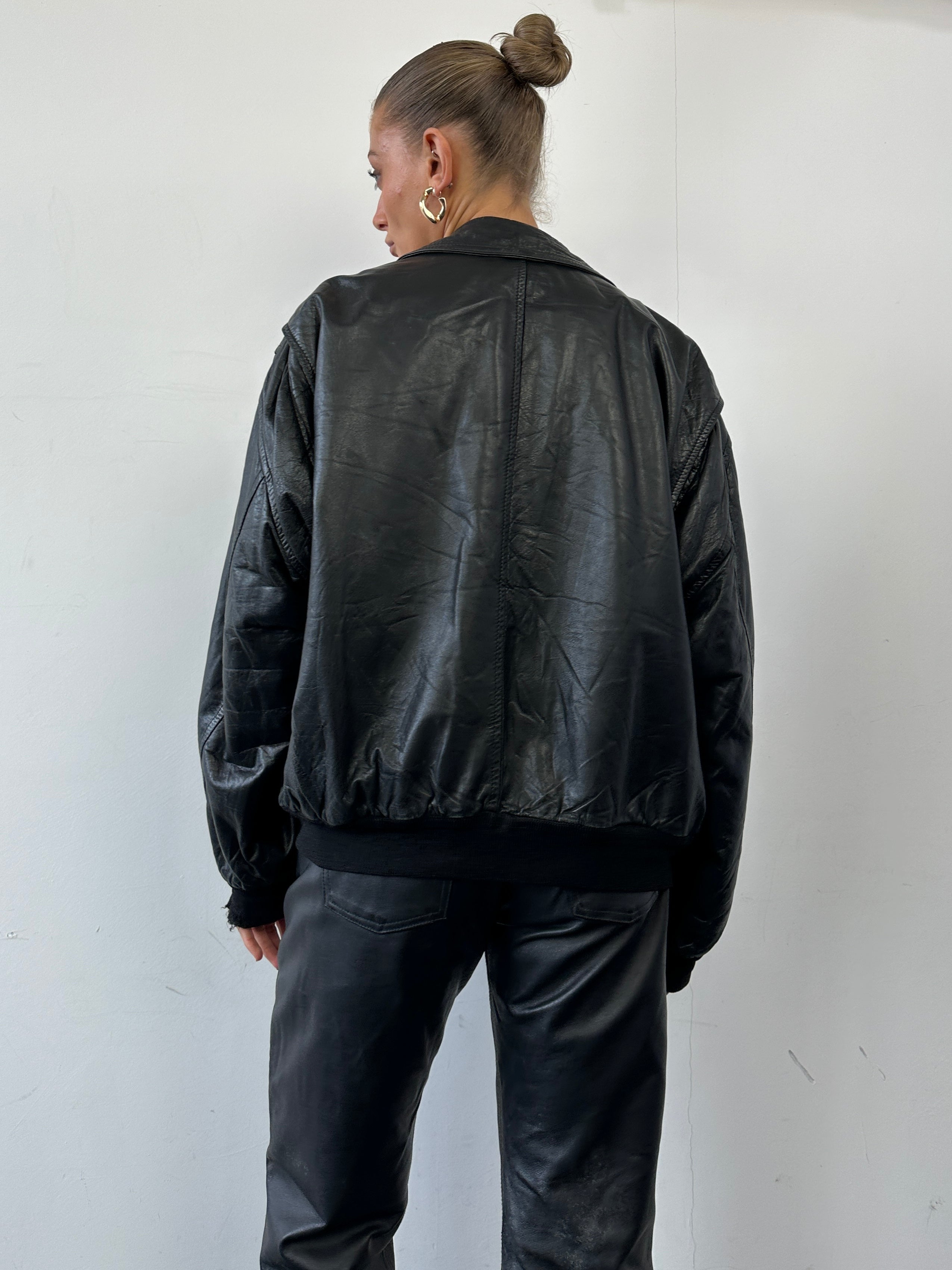 Vintage leather bomber jacket in size large, featuring classic design and durable material, displayed on a hanger.