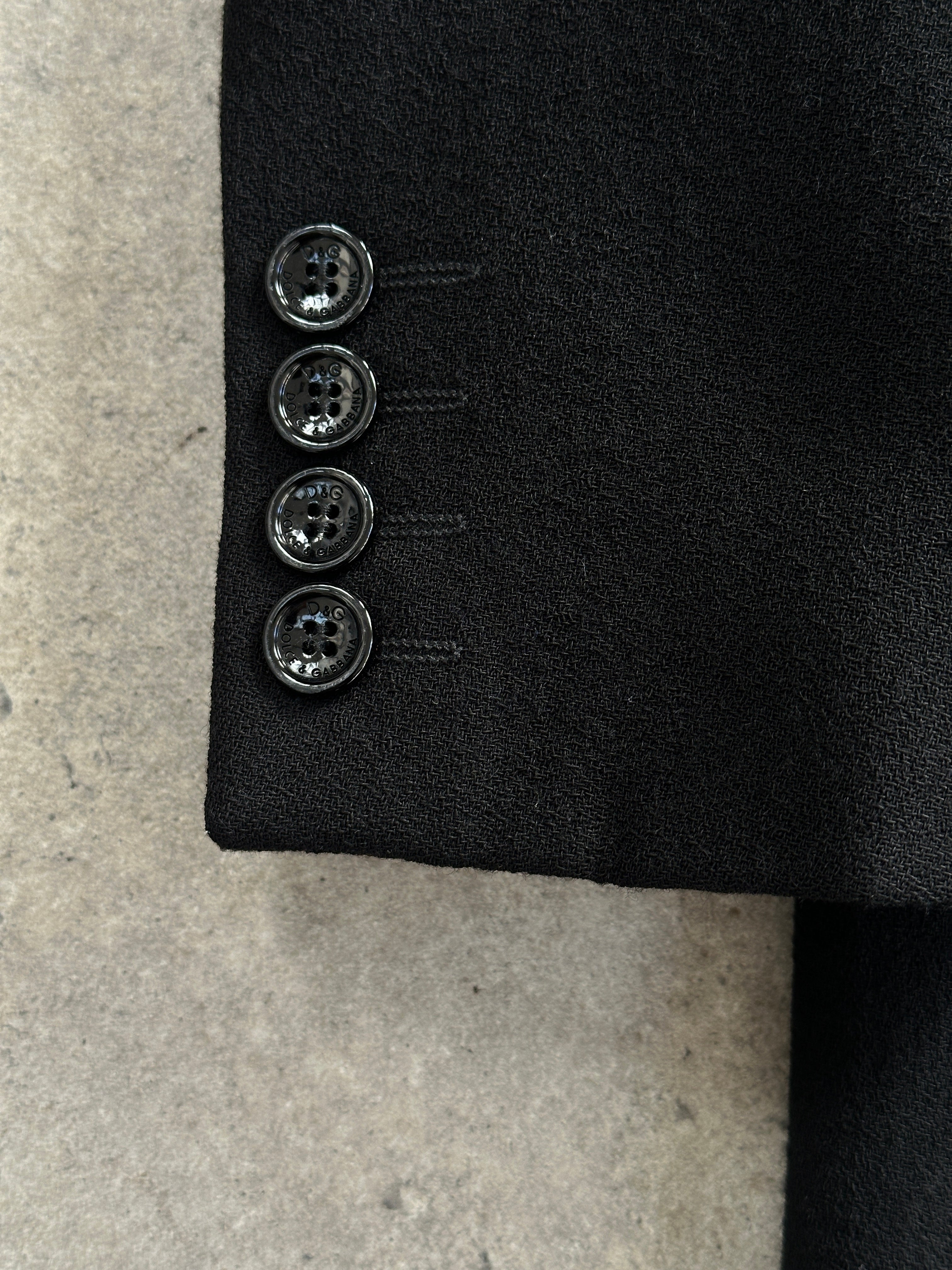 Dolce & Gabbana pure wool single-breasted coat in size M, displayed on a hanger with a tailored fit and classic design.