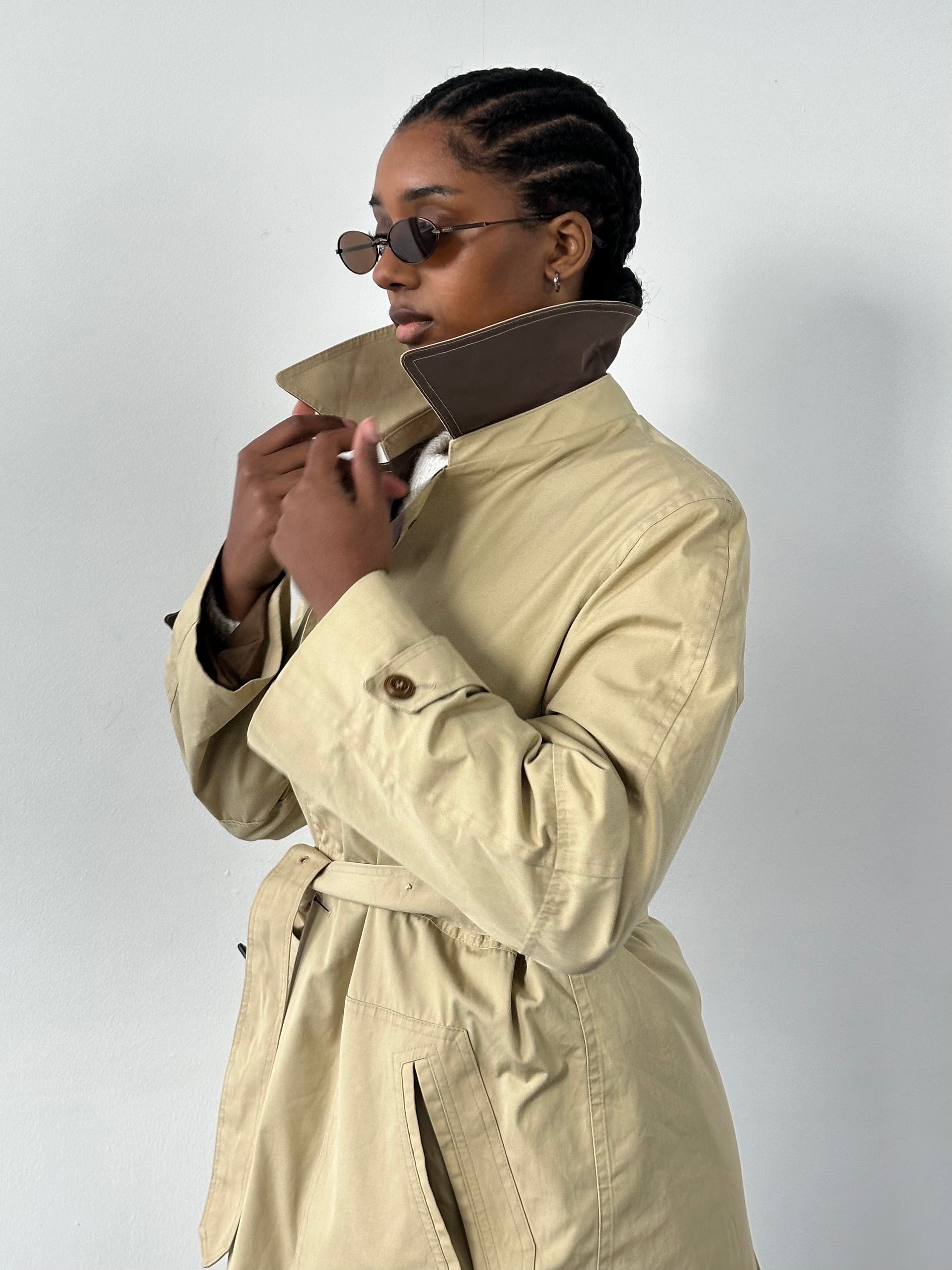 Christian Dior 1980s cotton belted trench coat in beige, stylish and classic, displayed on a hanger with visible belt and button details.