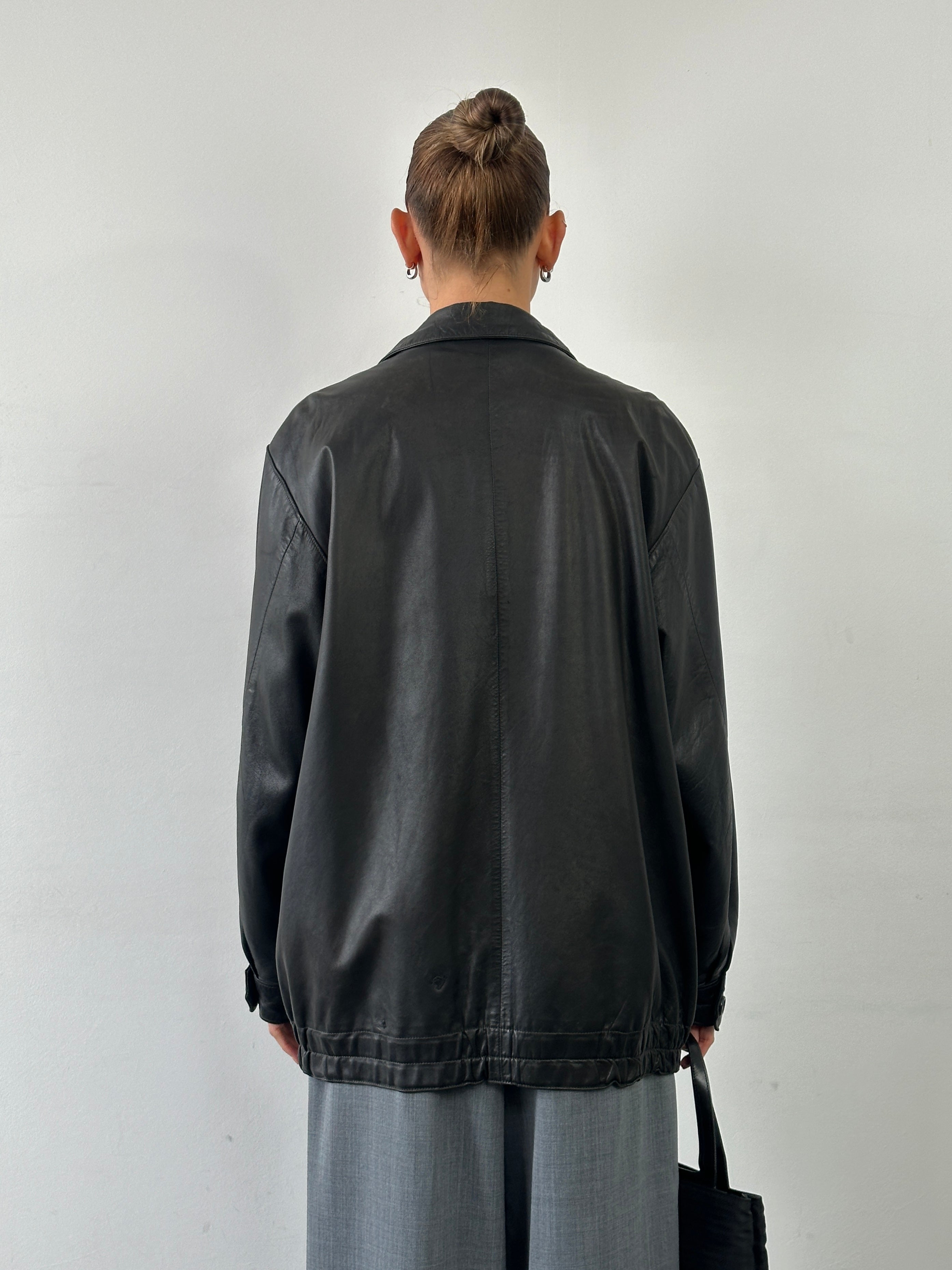 Vintage leather bomber jacket in XL size featuring a classic minimal design with a smooth leather finish and ribbed cuffs.