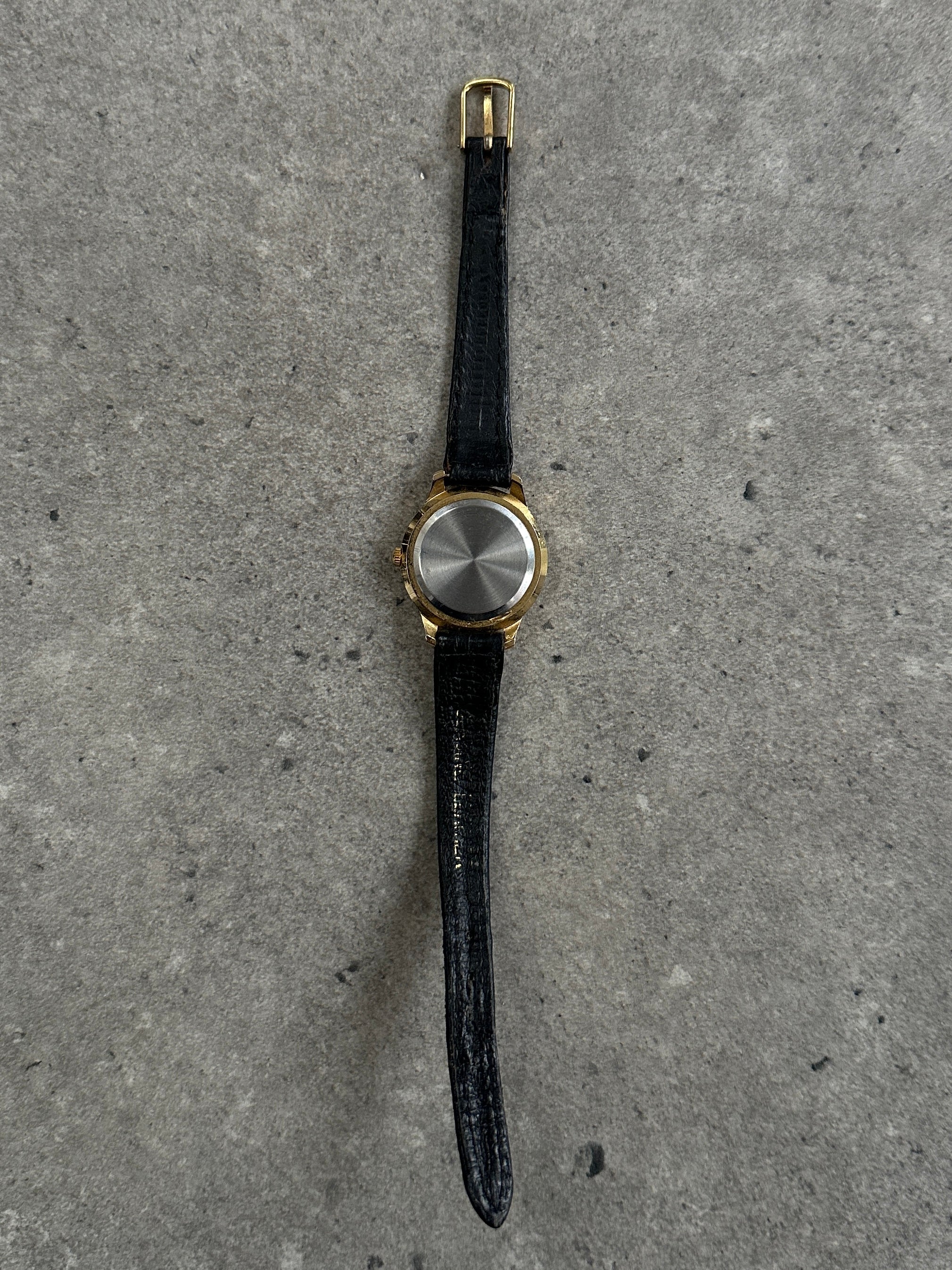 Vintage 1990s gold tone round quartz watch with classic design and analog display.