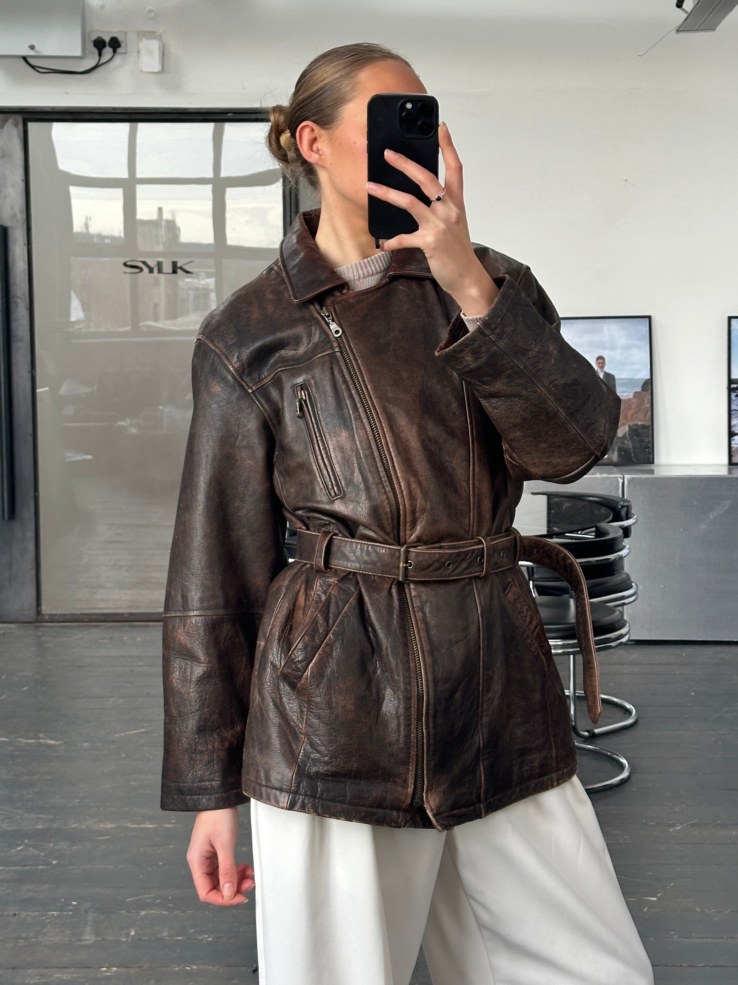 Vintage 1980s aged leather jacket with belt, in size L, featuring rugged style and distressed leather texture.