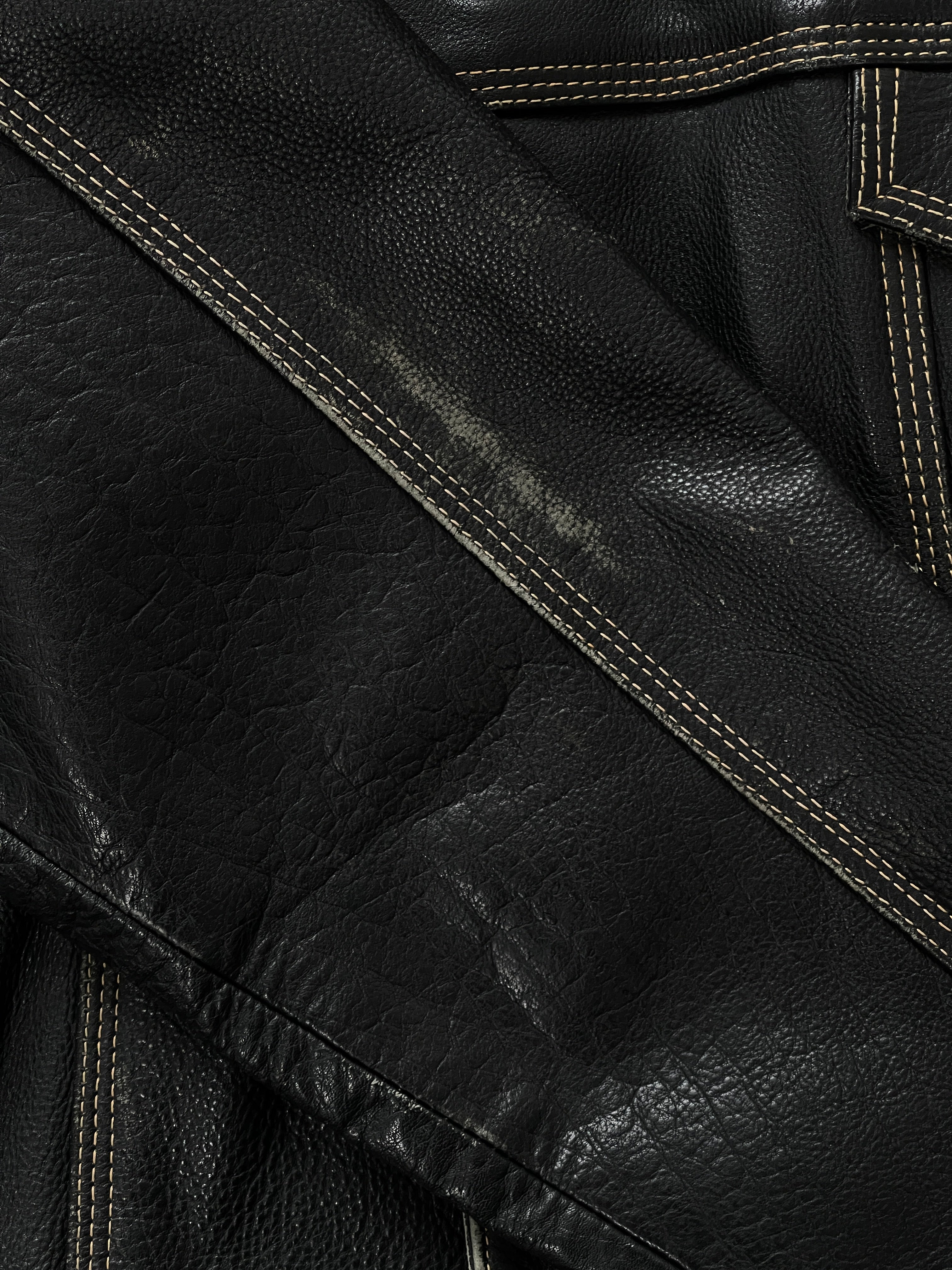 Vintage 1990s leather boxy jacket in black, featuring a classic design with a structured fit, displayed on a hanger.