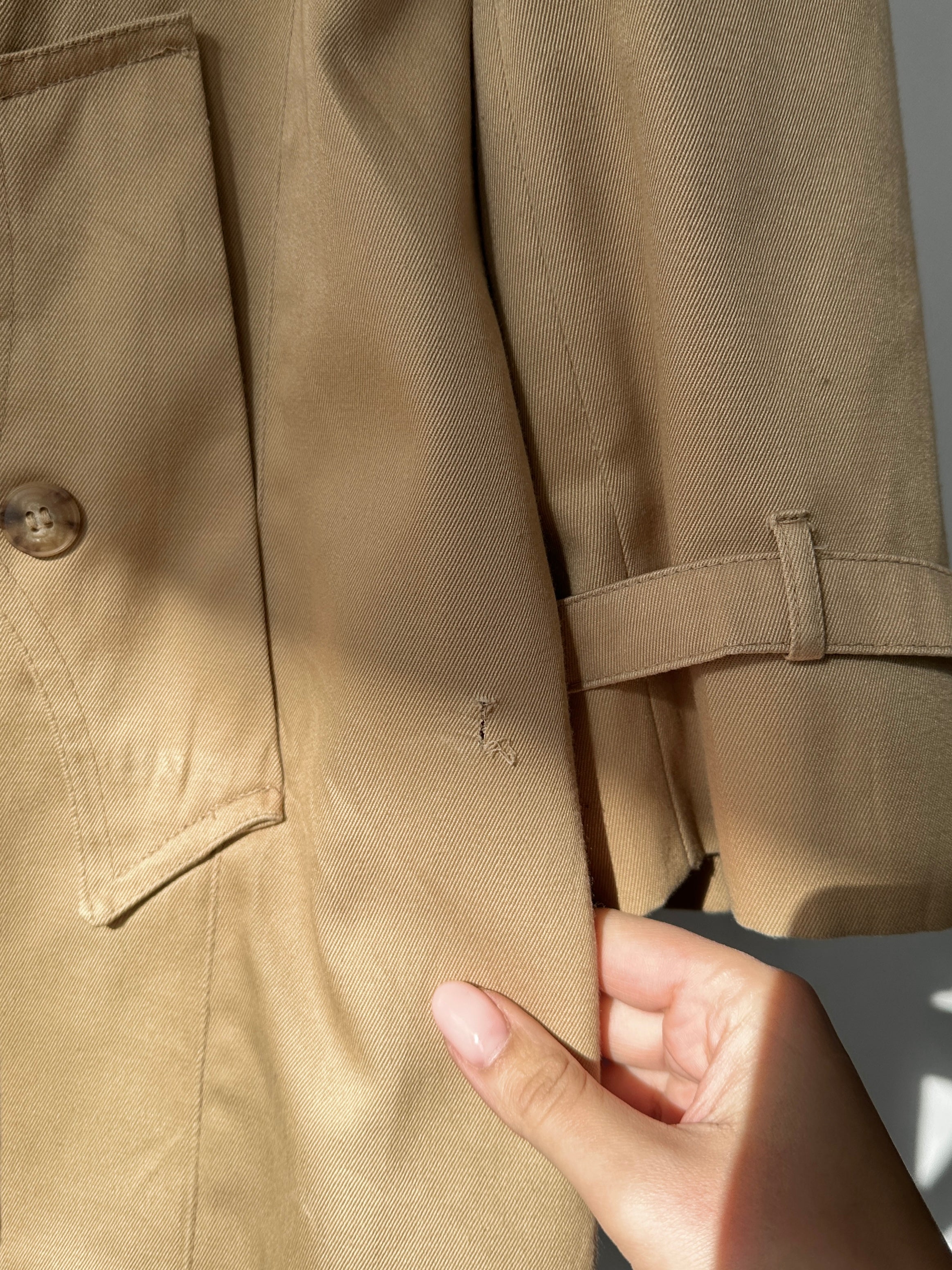 Christian Dior cotton double-breasted trench coat in size L/XL displayed on a hanger with classic design and neutral color.