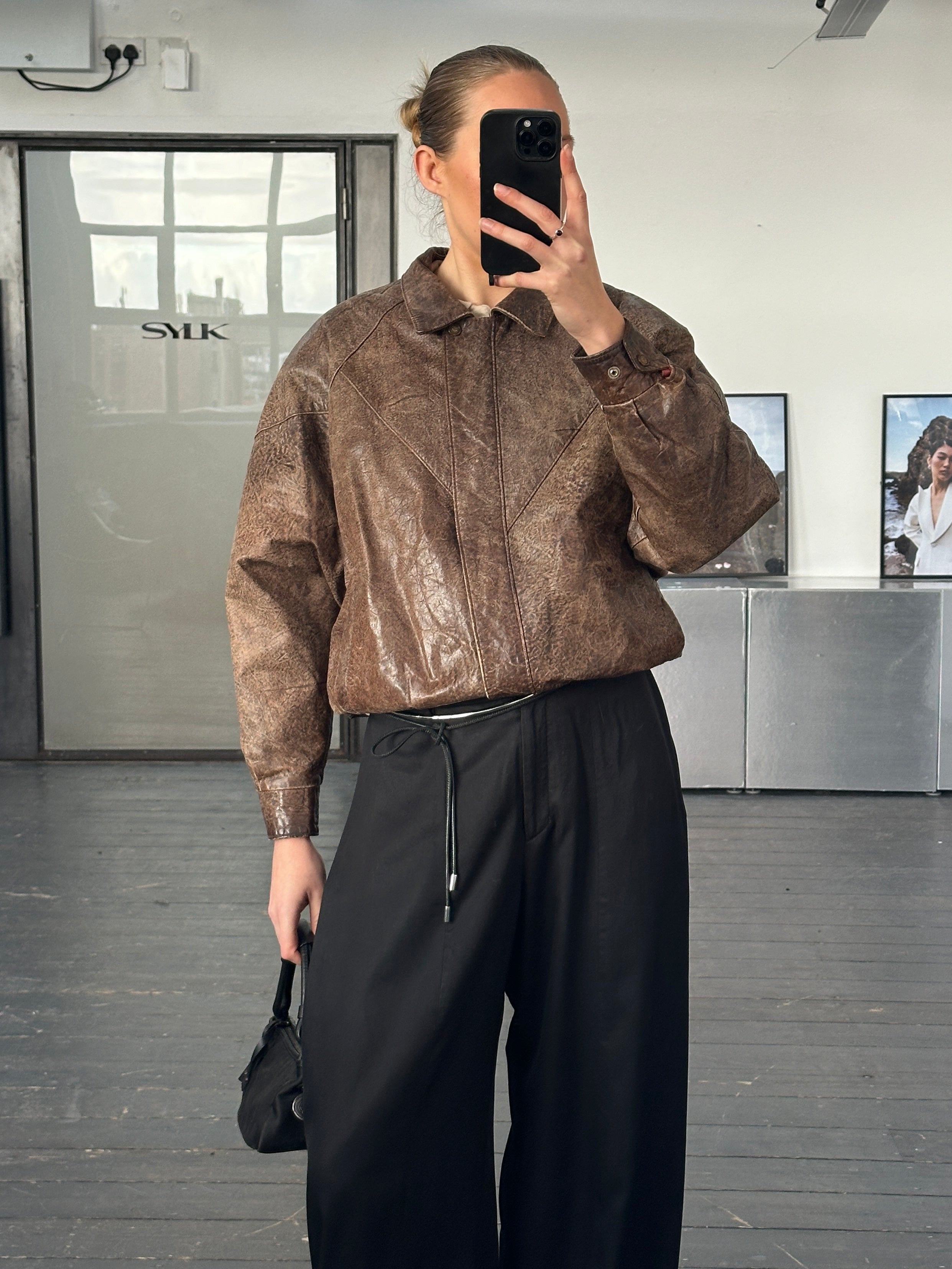 Vintage 1980s aged leather jacket in size small, featuring distressed brown leather and classic biker style.