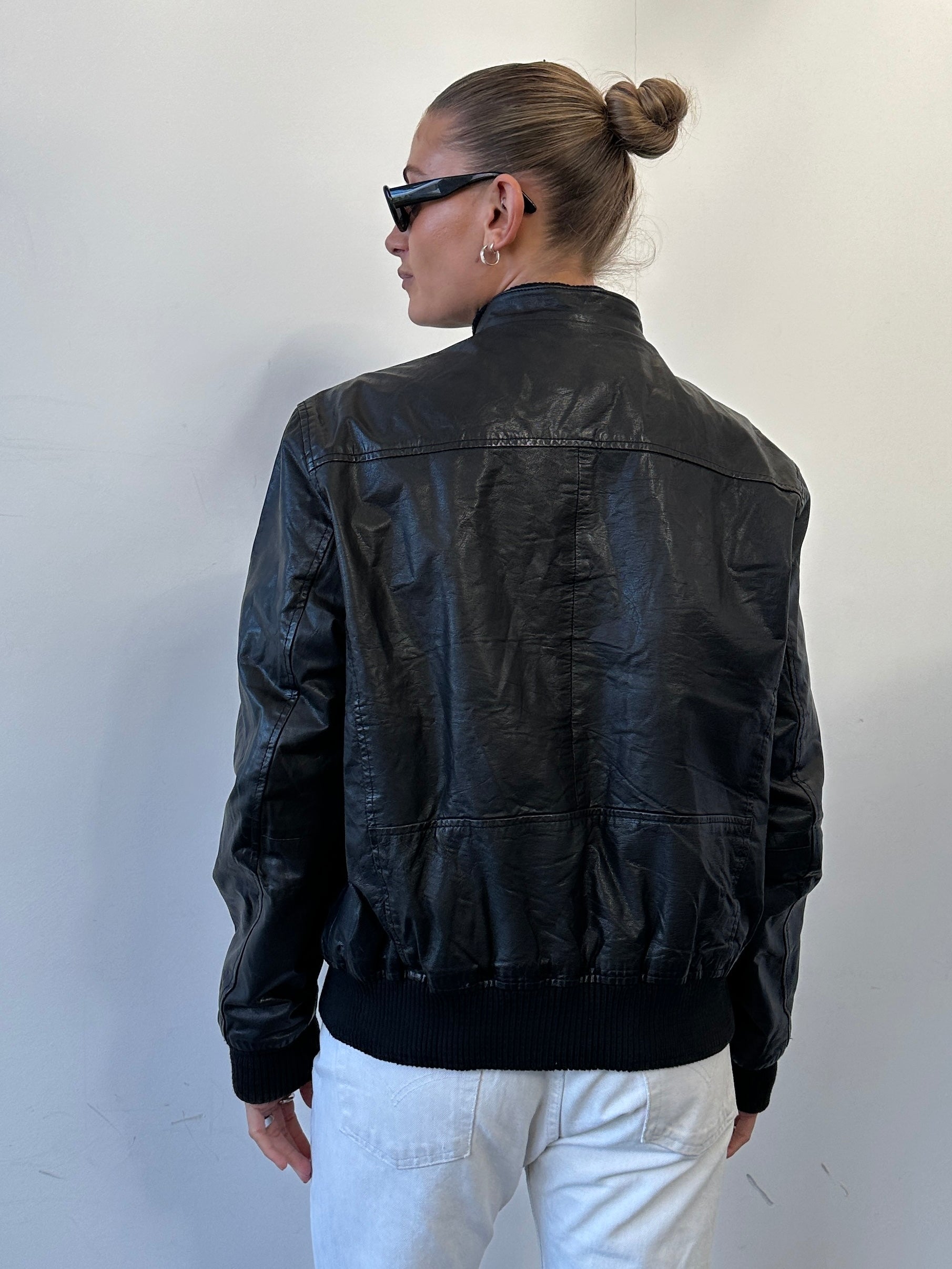 Conbipel Moto leather bomber jacket in black, with ribbed cuffs and collar, displayed on a hanger.