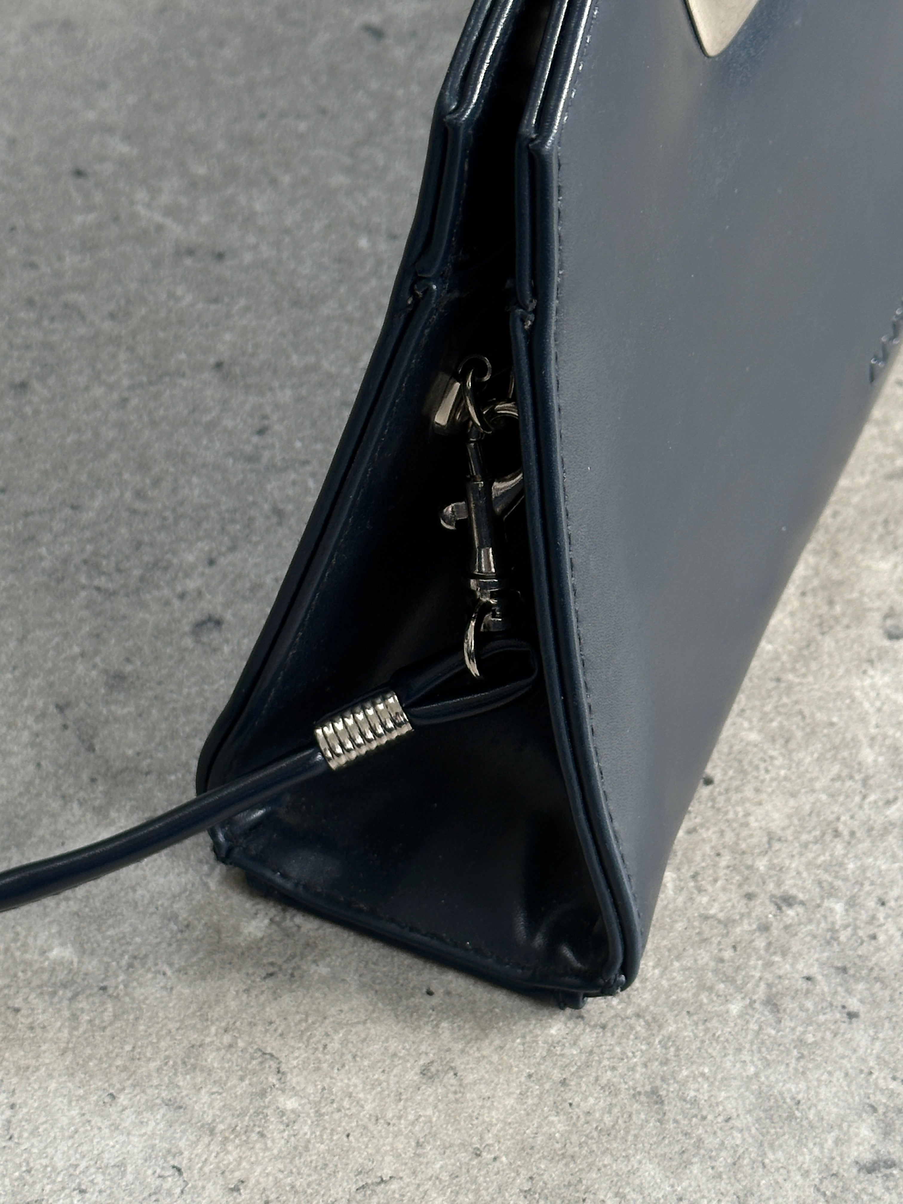 Vintage leather chrome crossbody clutch bag with adjustable strap and sleek design, perfect for stylish everyday use.