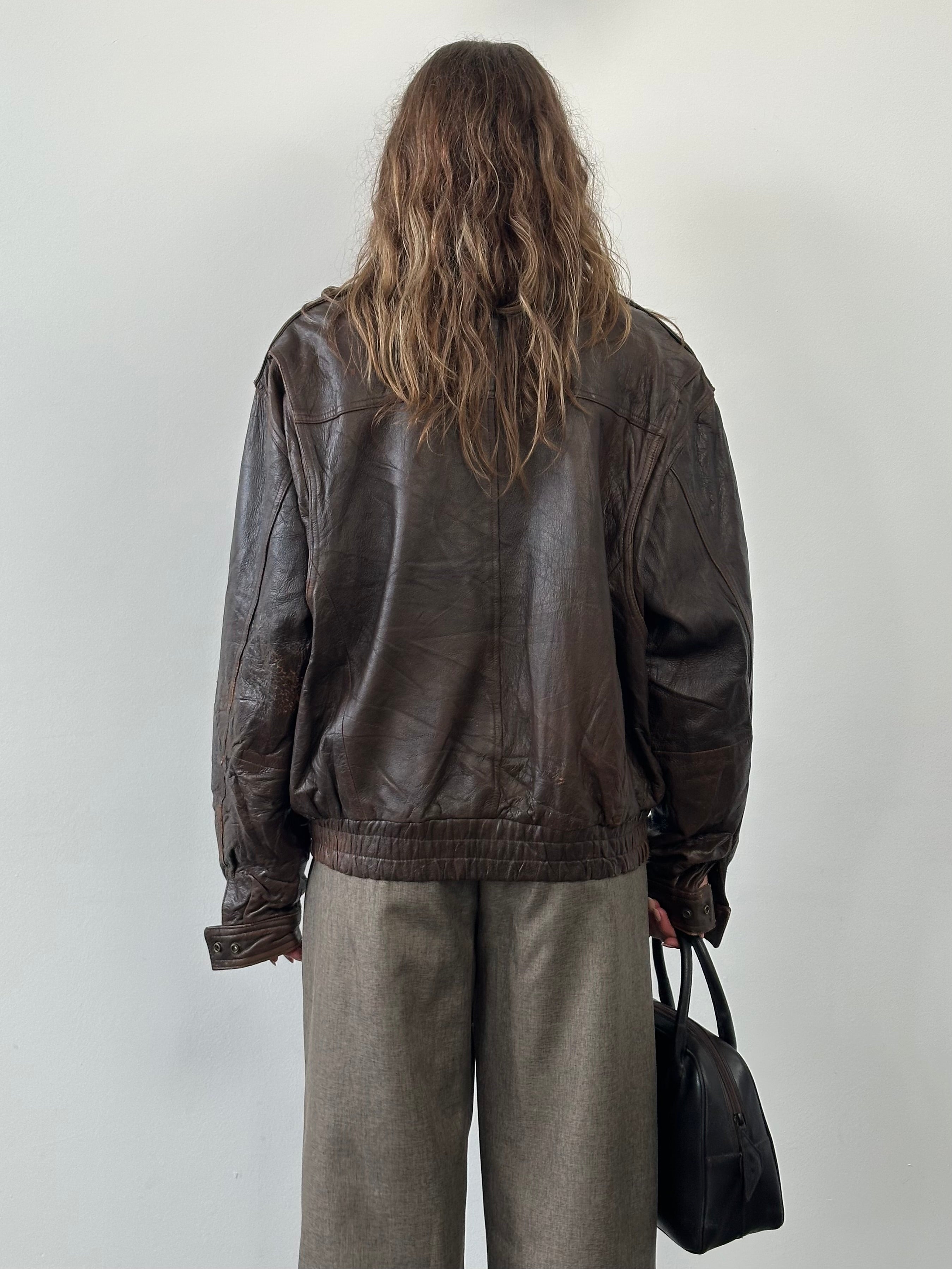 Vintage 1990s distressed leather bomber jacket in XL, featuring a rugged design with visible wear and classic detailing.