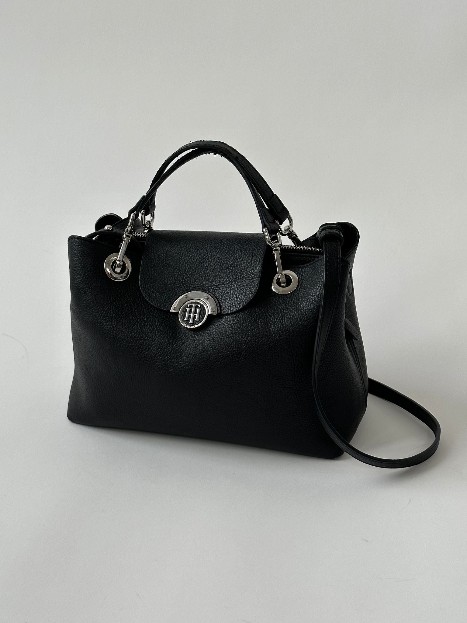 Tommy Hilfiger crossbody bag with adjustable strap, featuring classic logo design and sleek black leather finish.