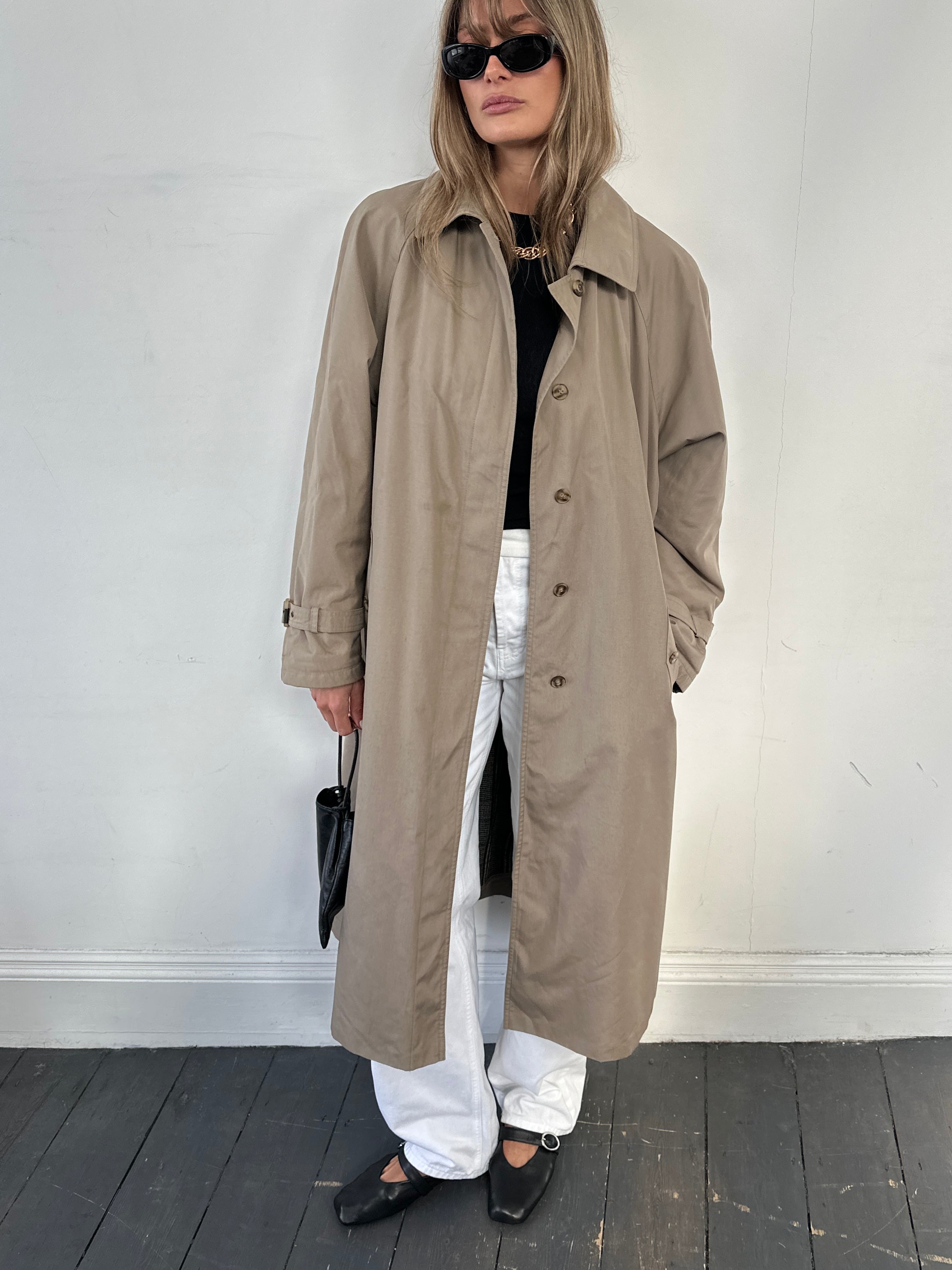 Vintage water-resistant trench coat with concealed placket, mid-length style, in size M/L, featuring classic design and durable fabric.