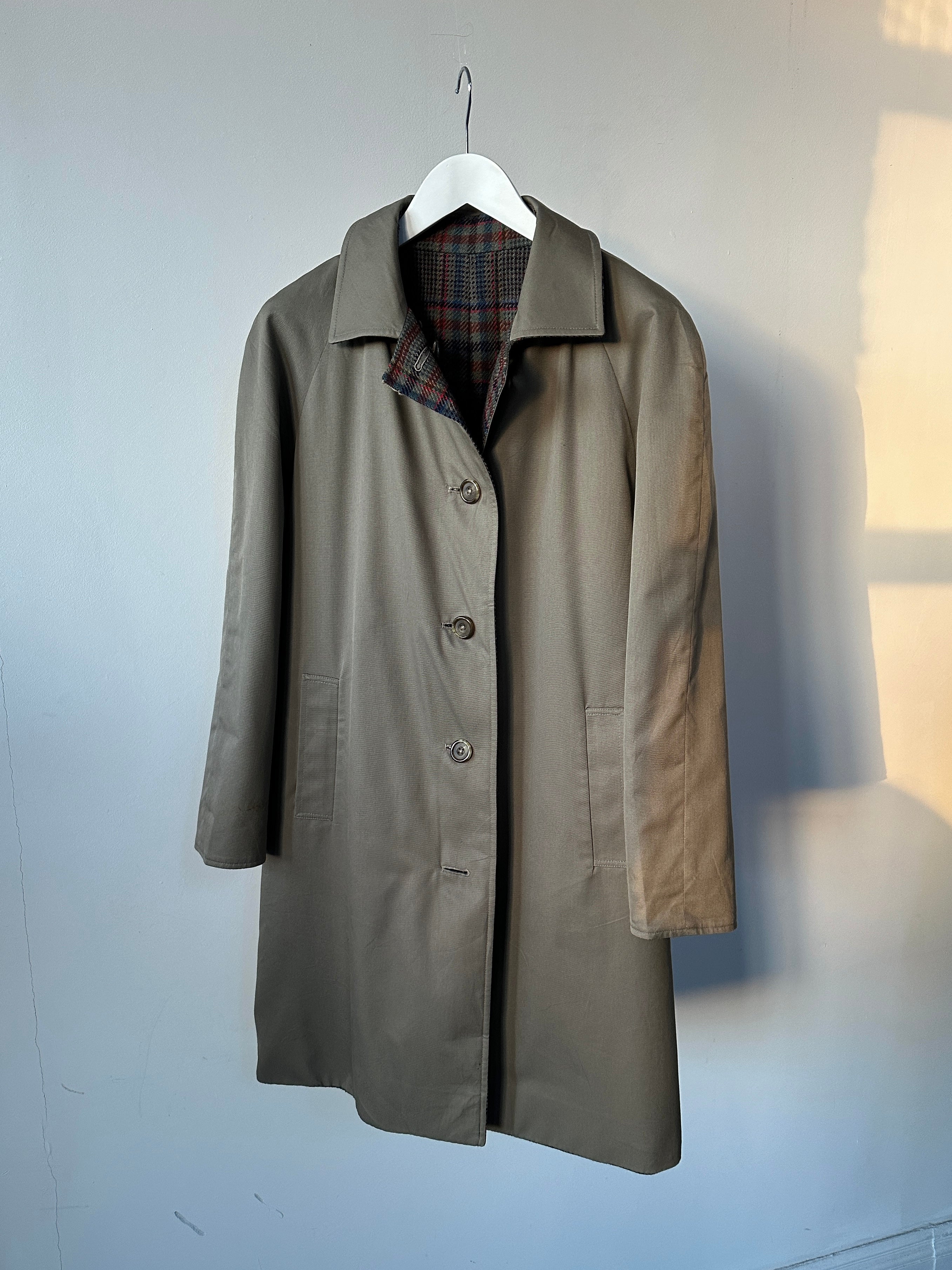 Vintage British reversible wool trench coat displayed on a hanger, showing both classic outer fabric and contrasting interior design.