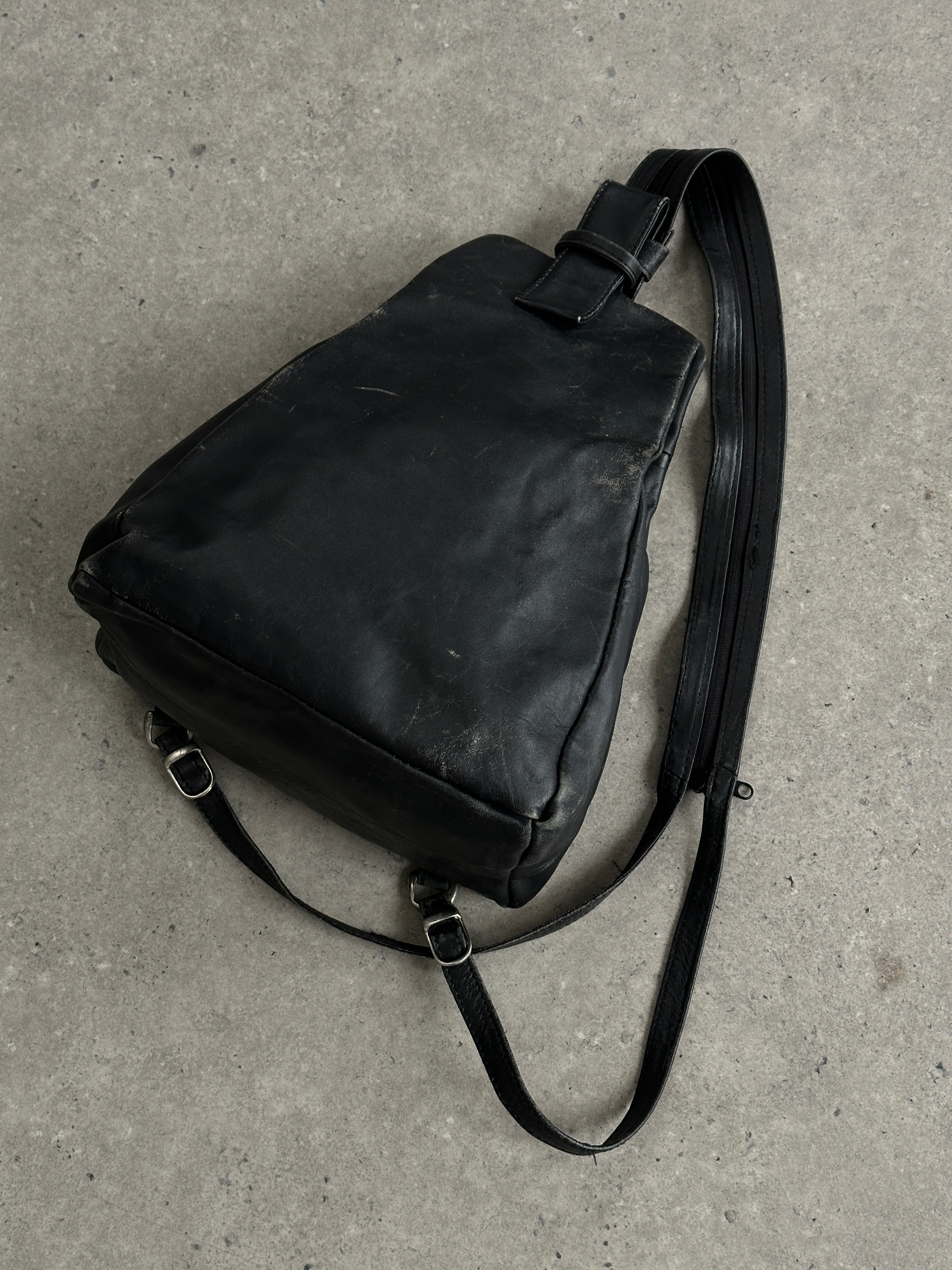 Vintage distressed faux leather rucksack crossbody bag with adjustable strap and vintage detailing.