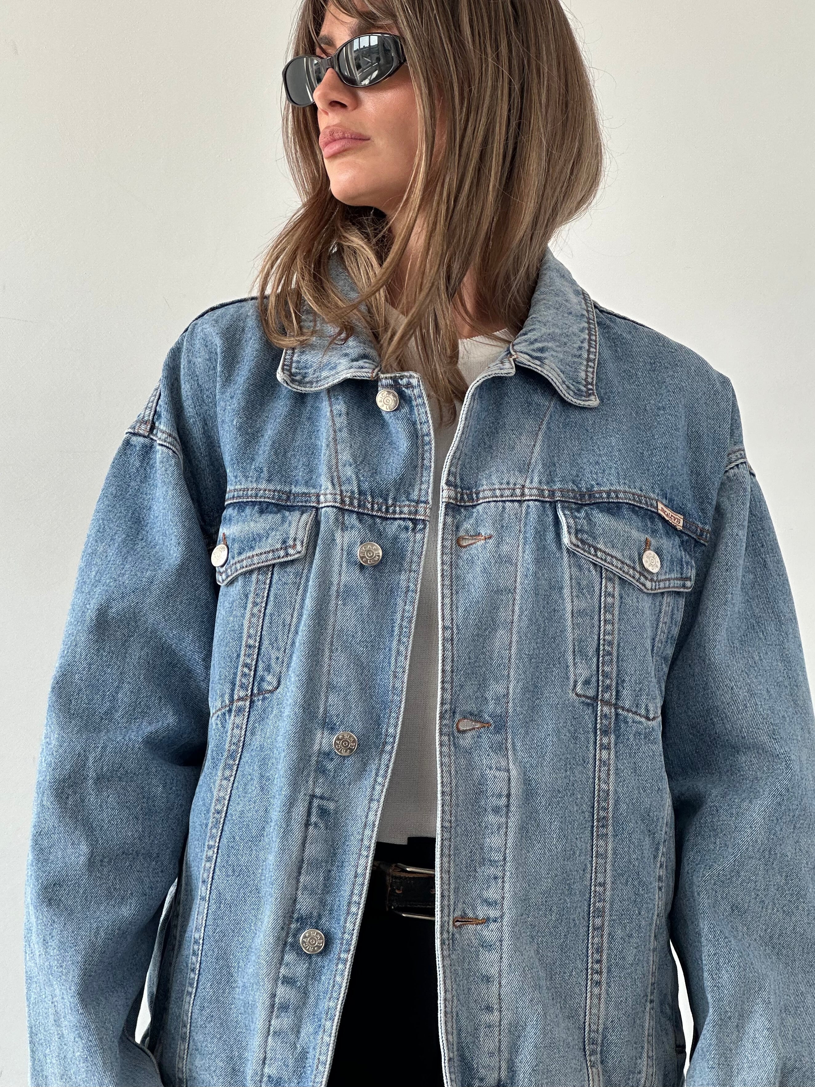 Vintage oversized denim jacket in XL size, featuring classic blue wash and relaxed fit, displayed on a hanger.