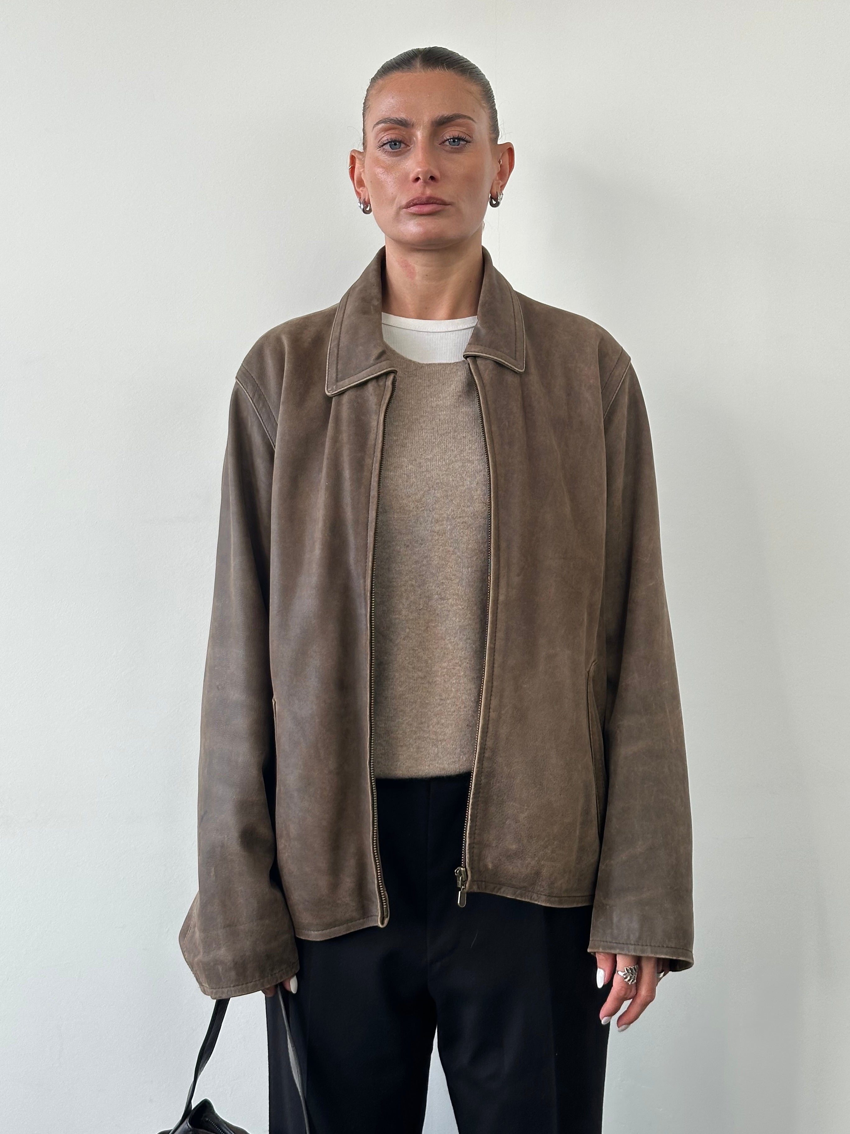 Vintage distressed leather jacket in size large, featuring rugged textures and classic design, displayed on a hanger.
