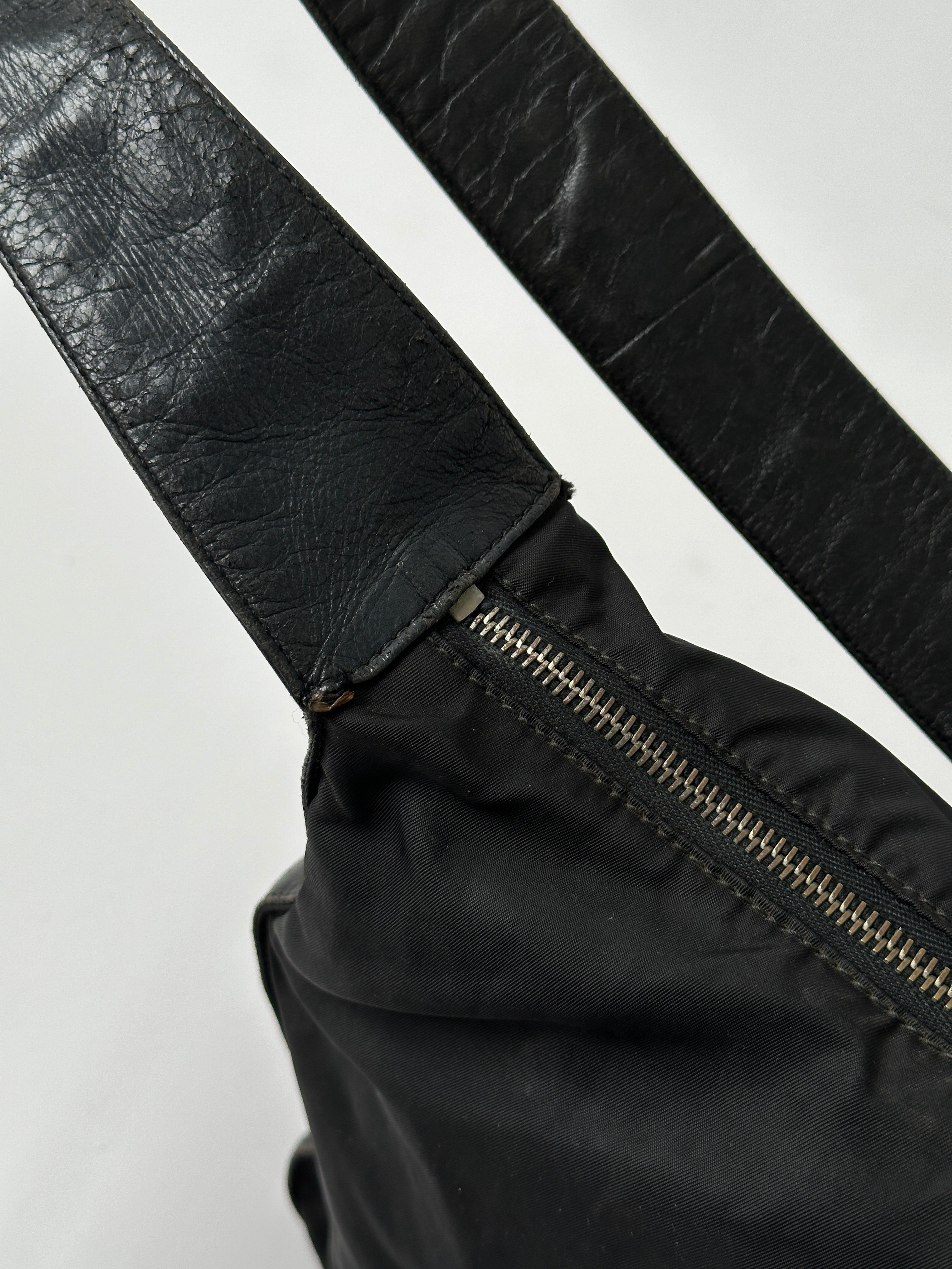 Prada nylon and leather crossbody bag with adjustable strap, sleek design, and iconic branding.